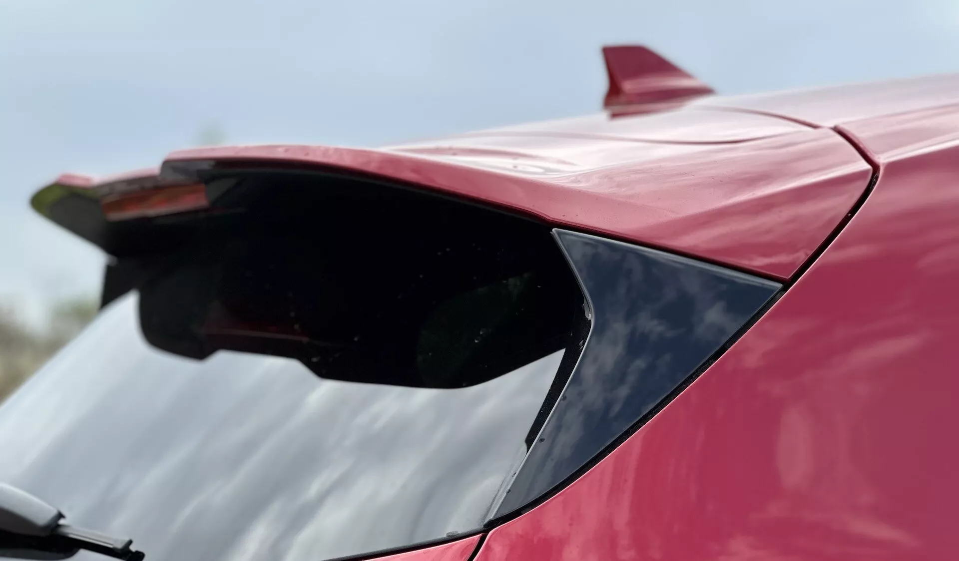 Inquadratura ravvicinata dello spoiler posteriore di una Ford Focus 2022 di colore rosso, che mette in evidenza il suo design aerodinamico e la finitura lucida da una prospettiva in basso