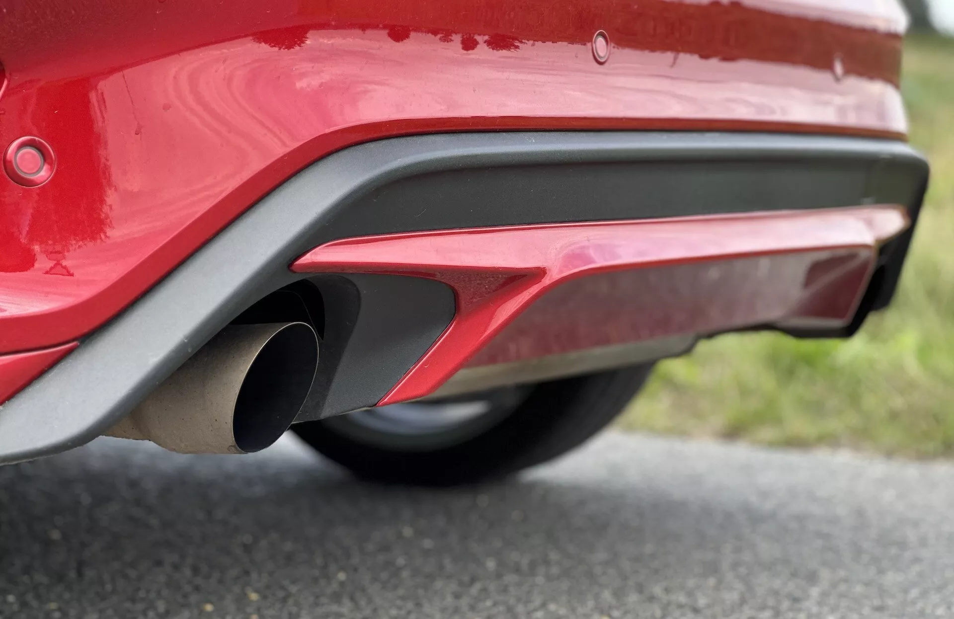 Primo piano della sezione posteriore inferiore di una Ford Focus 2022 che mostra un paraurti rosso lucido, un tubo di scarico metallico, design aerodinamico sportivo e sensori di parcheggio riflettenti