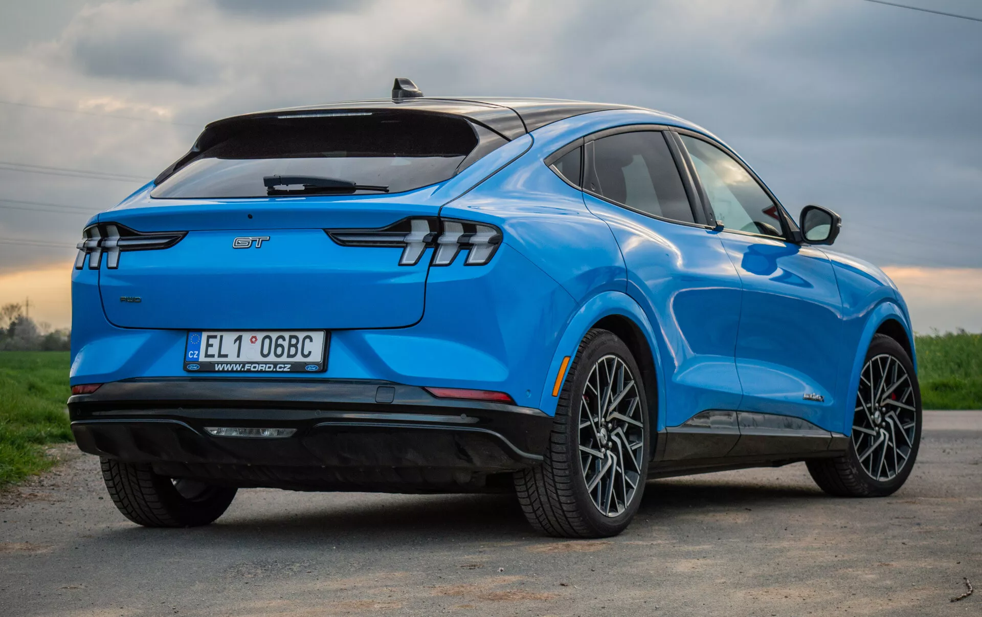 SUV elettrica blu Ford Mustang Mach-E 2020 vista da una prospettiva posteriore a tre quarti, che mette in evidenza il suo design aerodinamico elegante, luci posteriori LED moderne, ruote in lega a più razze, badge di veicolo elettrico e caratteristiche tecnologiche