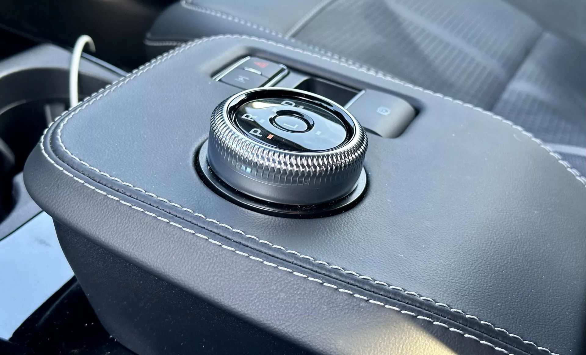 Vista ravvicinata dell’interno della Ford Mustang Mach-E 2020 con una manopola di controllo centrale sulla console, rivestita in pelle con cuciture bianche, che offre un’interfaccia ergonomica per il sistema di infotainment