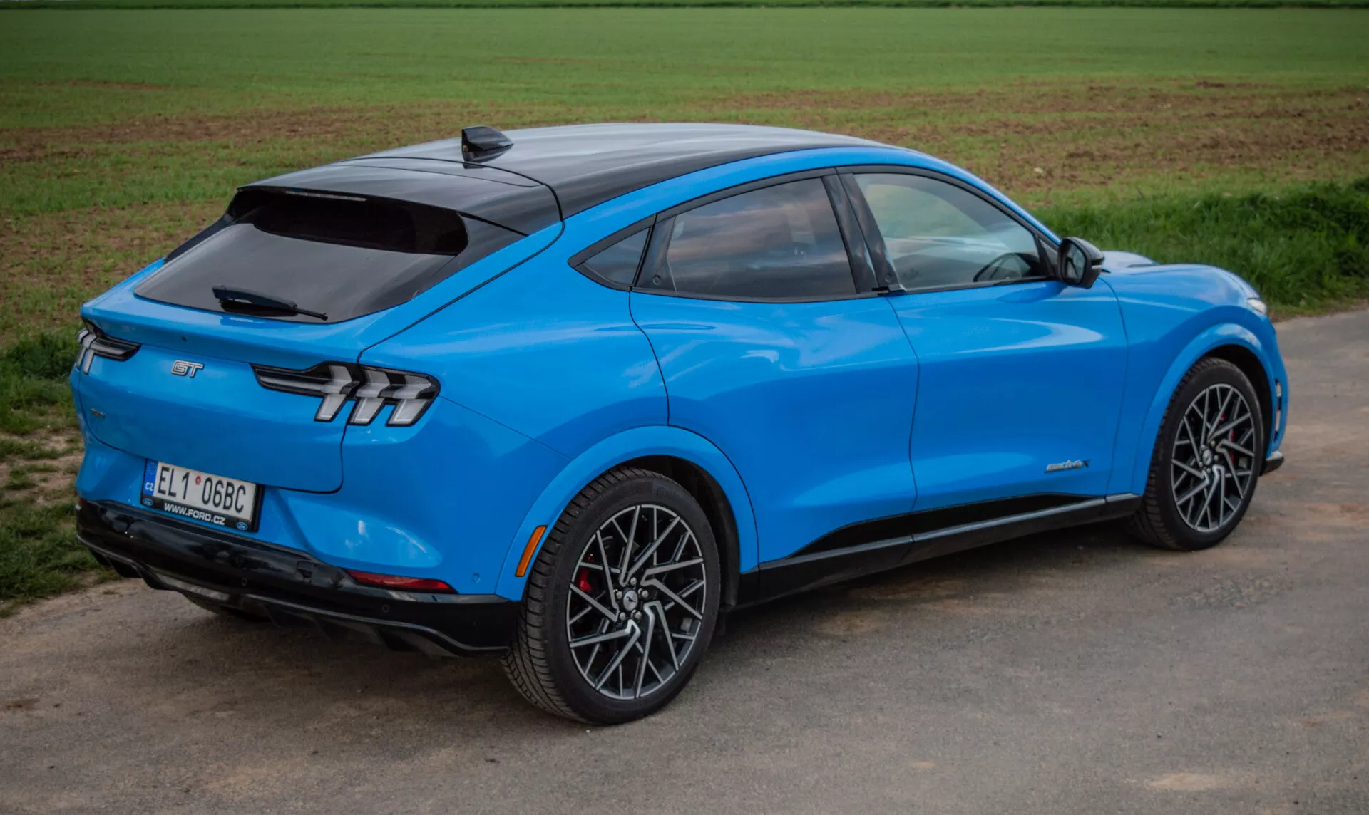 SUV elettrico Ford Mustang Mach-E 2020 blu brillante in una vista dinamica posteriore a tre quarti che evidenzia il design aerodinamico, eleganti luci posteriori e cerchi in lega sportivi, dimostrando tecnologia avanzata e propulsione elettrica.