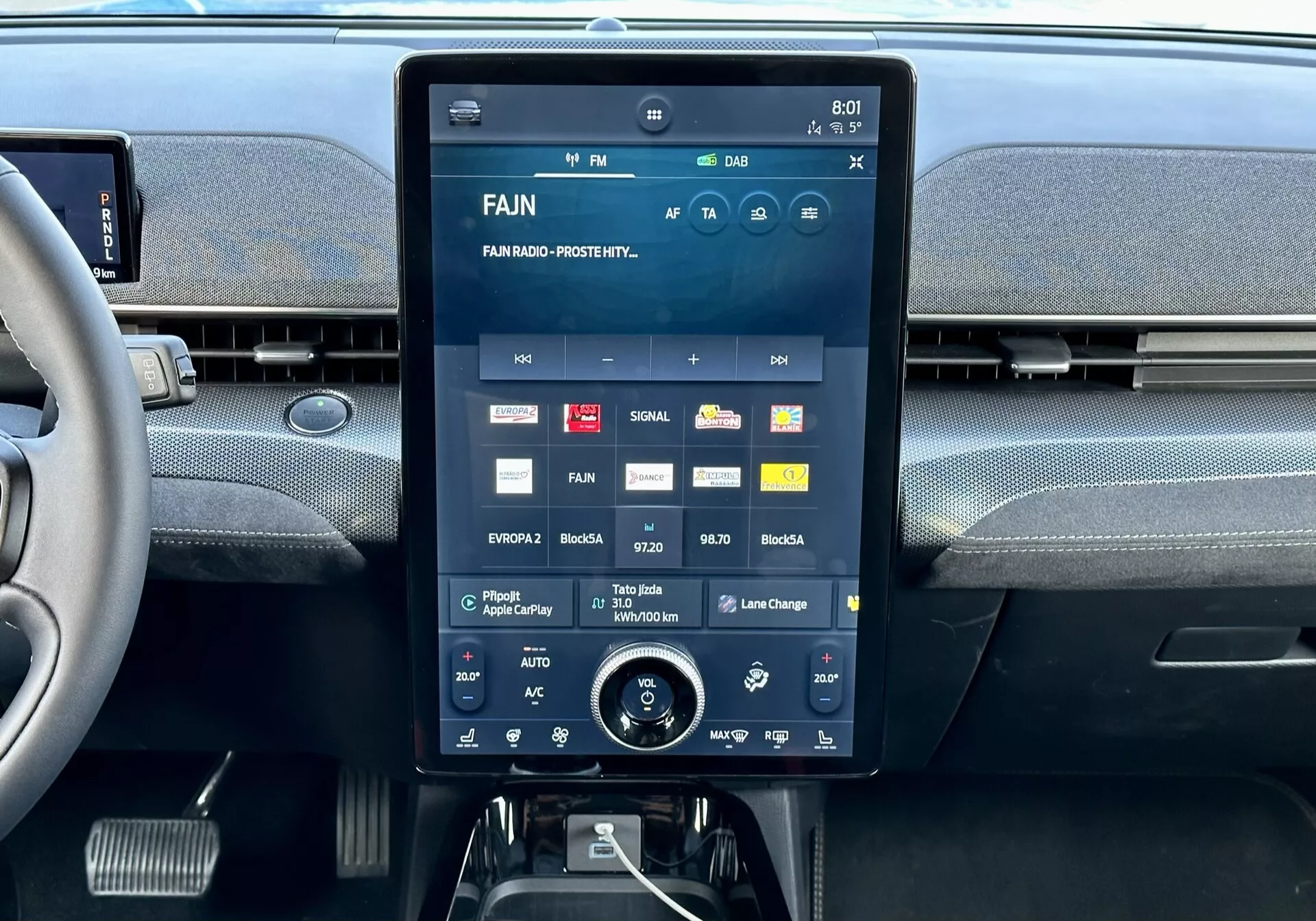 Console centrale interna della Ford Mustang Mach-E 2020 con un grande display touchscreen che mostra l'interfaccia multimediale con app e impostazioni, bocchette dell'aria integrate sopra e una manopola rotativa aggiuntiva per il controllo del clima sotto.