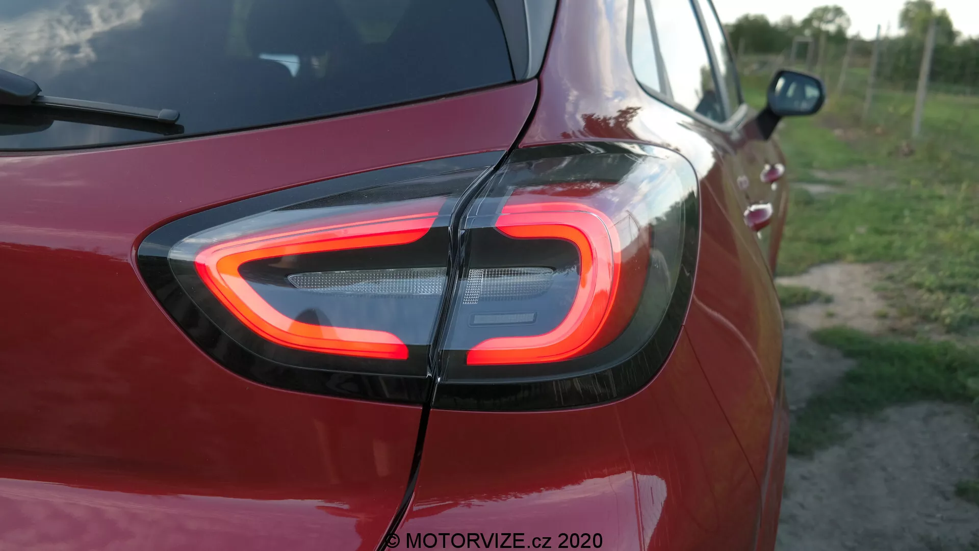 Dettaglio in primo piano della sezione posteriore della Ford Puma 2020, con il caratteristico fanale posteriore a LED a forma di C illuminato. Catturata da un'angolazione posteriore tre quarti, l'immagine mette in risalto la tecnologia avanzata dell'illuminazione e il design moderno, con la filigrana 'MOTORVIZE.cz 2020' che ne indica la fonte.