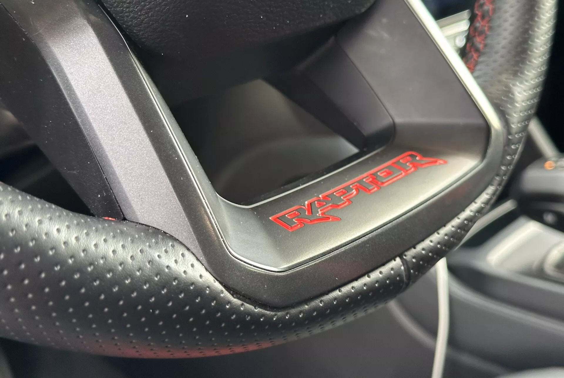 Vista ravvicinata di un volante Dodge Viper che mostra la pelle forata con cuciture rosse e il badge 'Viper', indicando un interni di auto sportiva e di lusso.