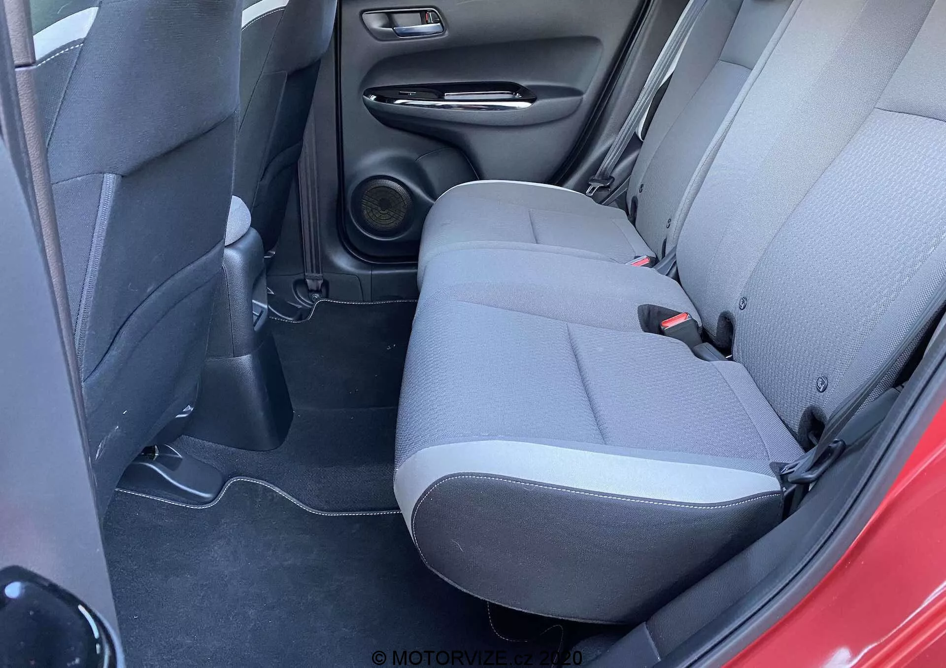 Vista interna della Honda Jazz 2020 (Jazz-Crosstar), che mostra l'area dei sedili posteriori da un angolo leggermente elevato, evidenziando la tappezzeria a due tonalità, il sistema di altoparlanti e gli elementi di design pratici.