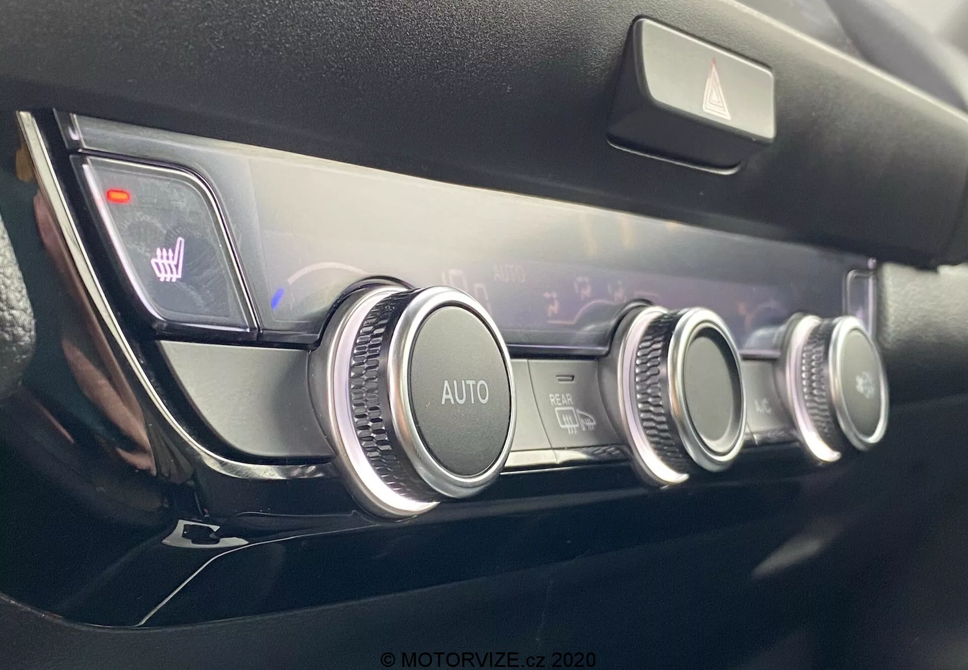 Vista ravvicinata del moderno pannello di controllo del clima della Honda Jazz 2020 con tre quadranti circolari con finitura metallica, un sistema di climatizzazione automatico, impostazioni della temperatura a doppia zona indicate su un display digitale e icone illuminate del riscaldamento dei sedili, il tutto in un design del cruscotto di alta qualità e minimalista.