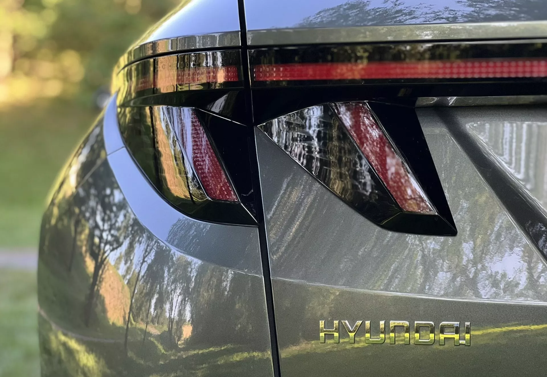 Vista ravvicinata della sezione posteriore della Hyundai Tucson 2020, mettendo in evidenza le luci posteriori LED angolari, il marchio HYUNDAI, lo spoiler posteriore integrato con luce freno e la finitura metallica lucida
