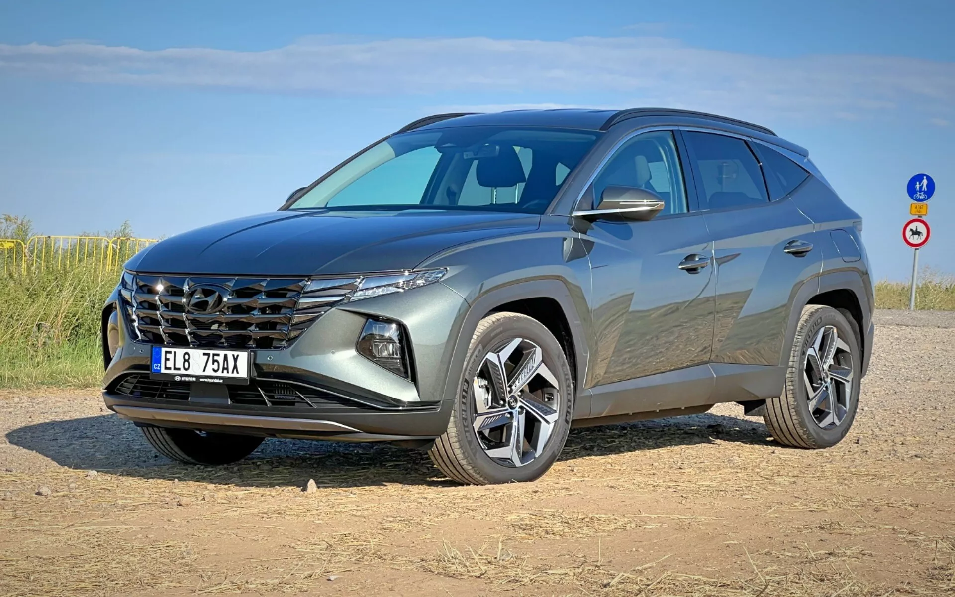 SUV moderno Hyundai Tucson 2020 raffigurato in vista frontale a tre quarti che mostra la sua griglia distintiva, fari eleganti, fascia anteriore, cofano scolpito e ruote in lega su una piazzola di terra sotto un cielo limpido