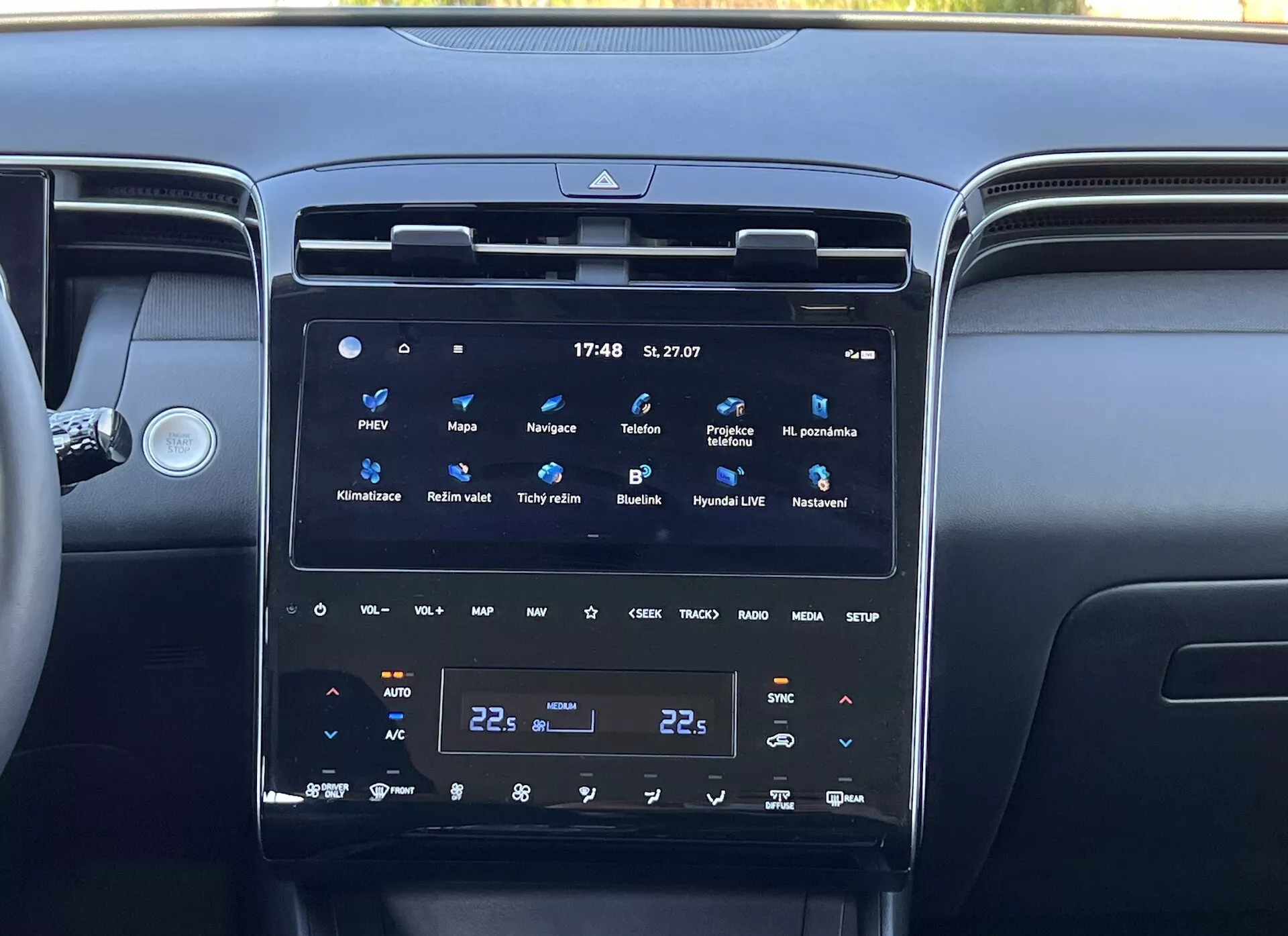 Interno della Hyundai Tucson 2020 che mostra la console centrale con un grande schermo touch verticale del sistema di infotainment, controllo climatico a doppia zona e bocchette d'aria circostanti, riflettendo la tecnologia moderna del veicolo e il lusso