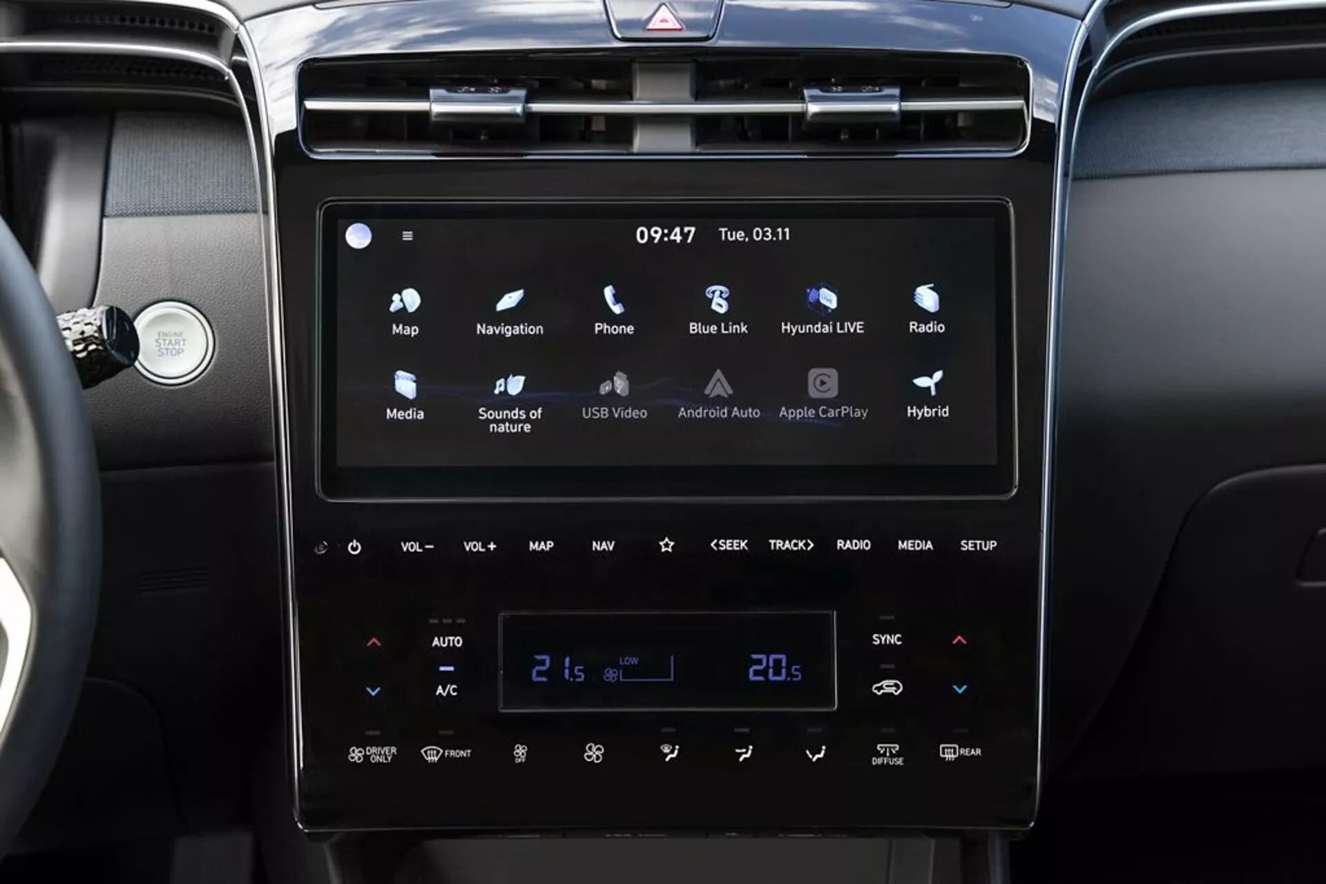 Interni Hyundai Tucson 2020 con sistema di infotainment moderno touchscreen con Android Auto e Apple CarPlay, controllo automatico del clima a doppia zona impostato a 21 gradi Celsius e indicatori di veicolo ibrido