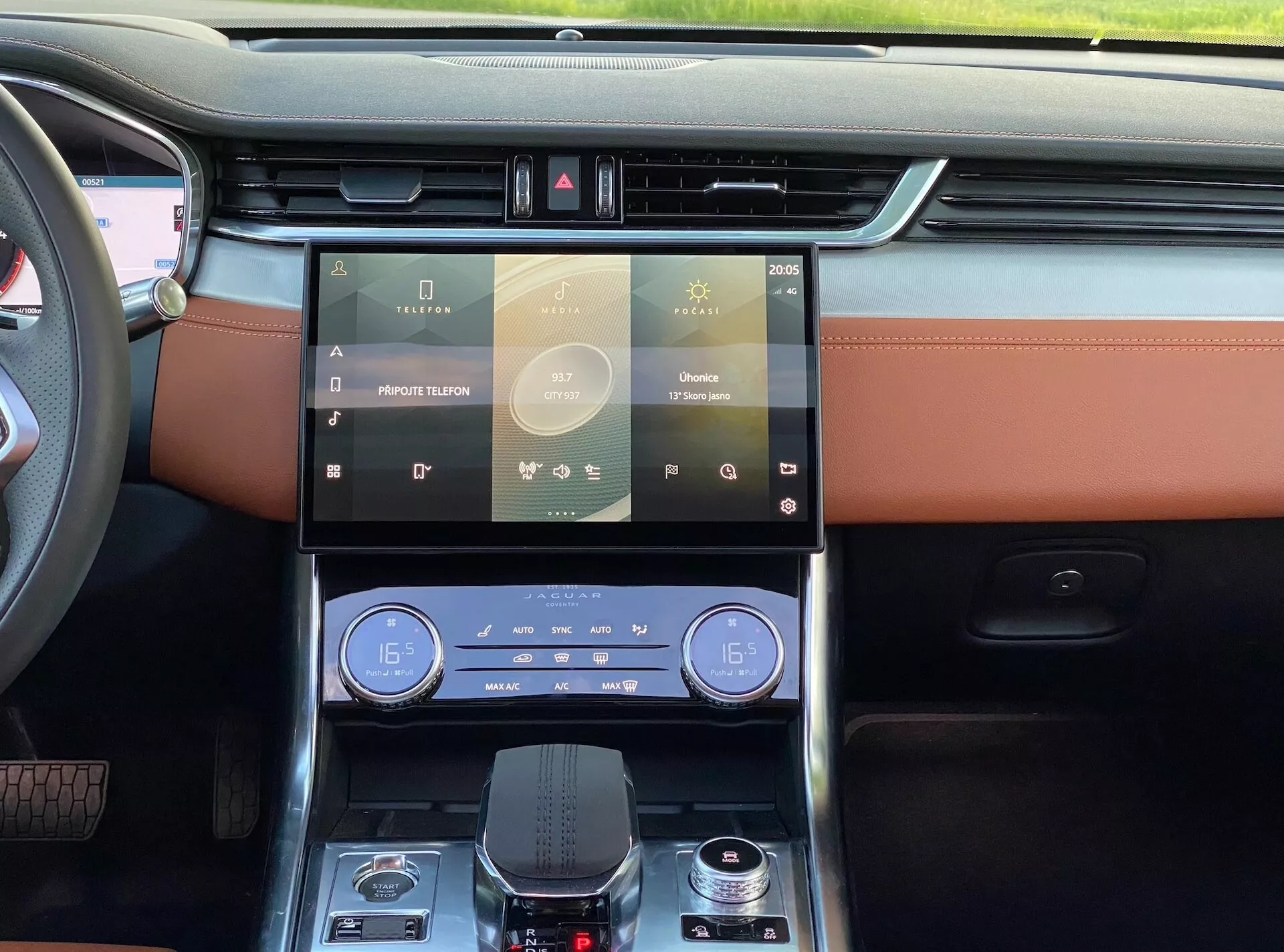 Vista interna della Jaguar XF 2021, che mostra il cruscotto con finiture in legno, doppio schermo touchscreen per sistemi di infotainment e controllo del clima, rivestimenti in pelle beige con cuciture a contrasto, selettore del cambio a rotore e funzioni tecnologiche avanzate dalla prospettiva del sedile anteriore.
