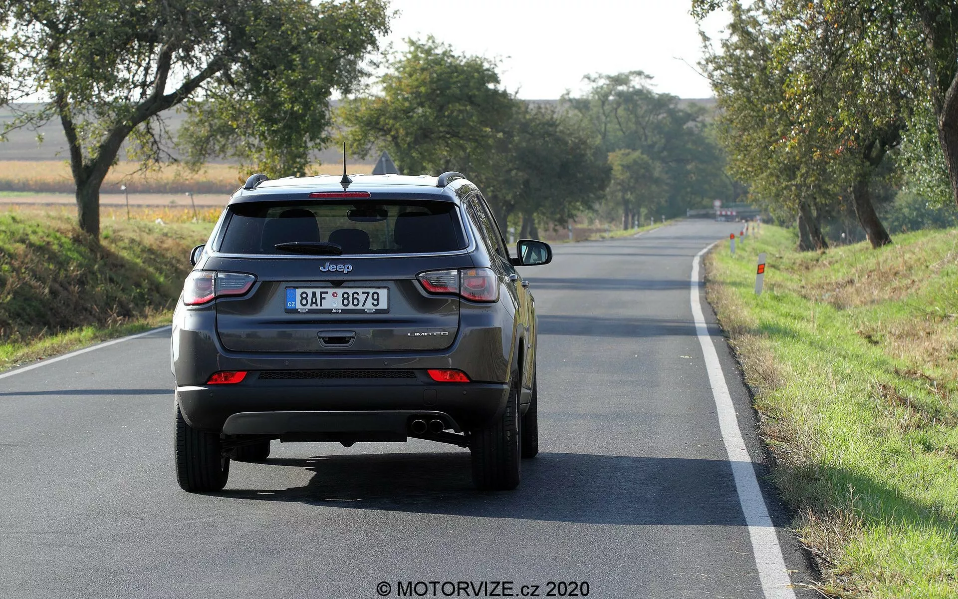 Vista posteriore di un Jeep Compass SUV 2017 su una strada a due corsie in pieno giorno, visibili il logo e il nome del modello, targa in stile europeo, luci posteriori LED, portellone chiuso con tergicristallo posteriore, terza luce di stop sullo spoiler posteriore, paraurti posteriore con riflettori, doppi tubi di scarico sul lato sinistro, ruote posteriori in lega, eventuali distintivi aggiuntivi che potrebbero indicare il livello di finitura o la trazione.