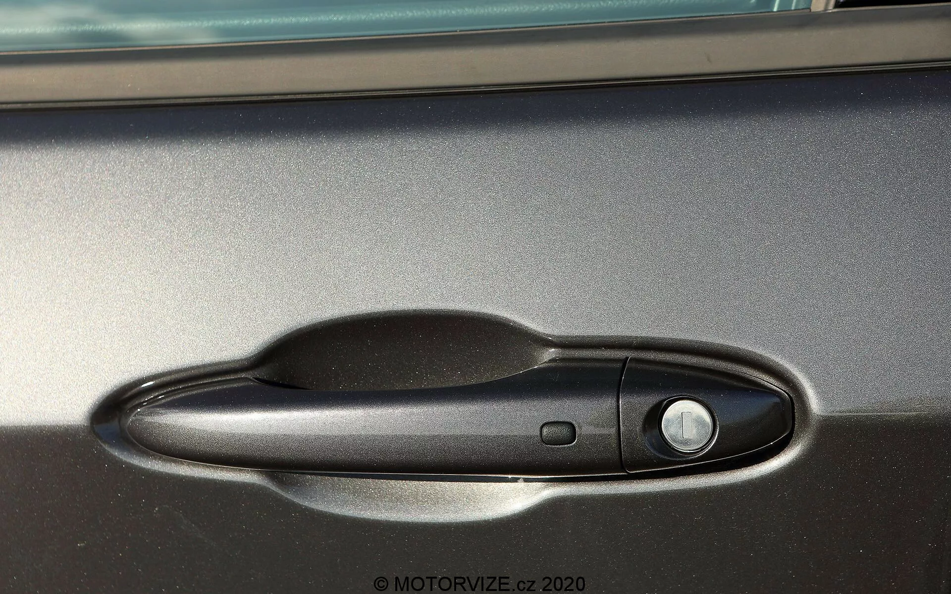 Vista laterale ravvicinata della maniglia della porta della Jeep Compass 2017, con maniglia nera a finitura opaca e pulsante di accesso keyless, catturata in luce naturale con rifinitura metallica visibile sopra.
