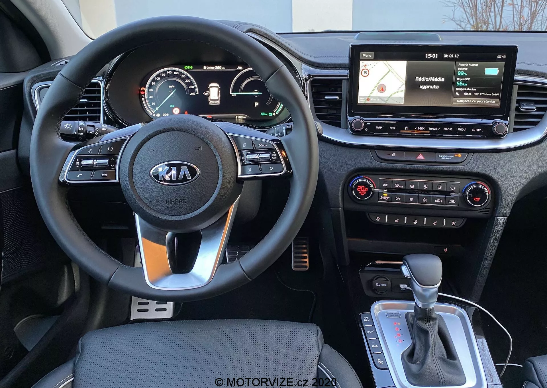 Vista interna di una Kia Ceed 2018 dalla prospettiva del conducente, che mostra un volante a tre razze con il logo Kia, controlli integrati nel volante, un quadro strumenti digitale/analogico, un display di infotainment con navigazione e interfaccia multimediale, controlli fisici del climatizzatore e una leva del cambio automatico con possibile selettore di modalità di guida o freno di stazionamento elettronico.