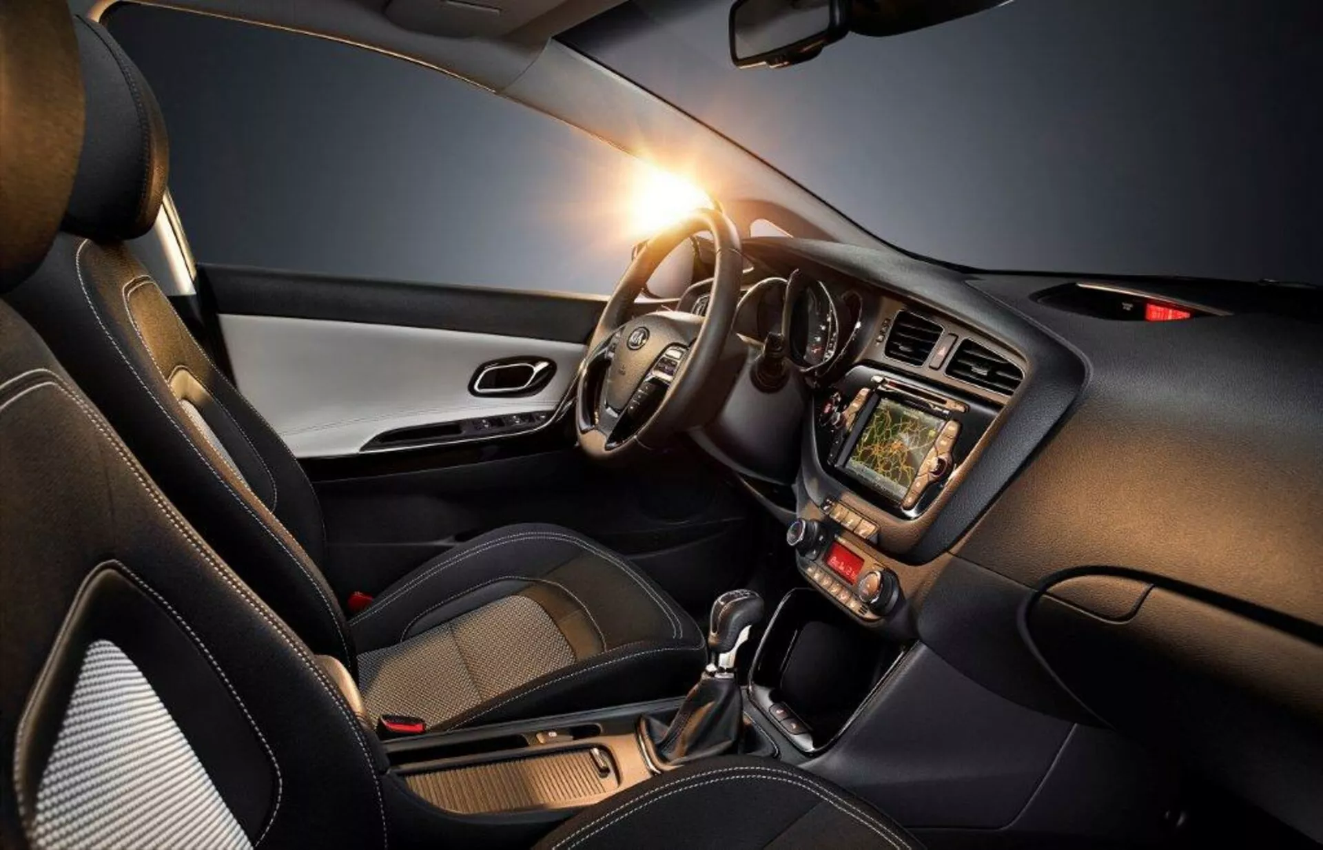 Interno della Kia Cee'd 2009 evidenziando il lato conducente con volante a sinistra, cruscotto, sistema di infotainment touchscreen, controlli del climatizzatore, leva del cambio automatica e accentuazioni di design moderno, enfatizzando tecnologia, comfort e aspetto sportivo
