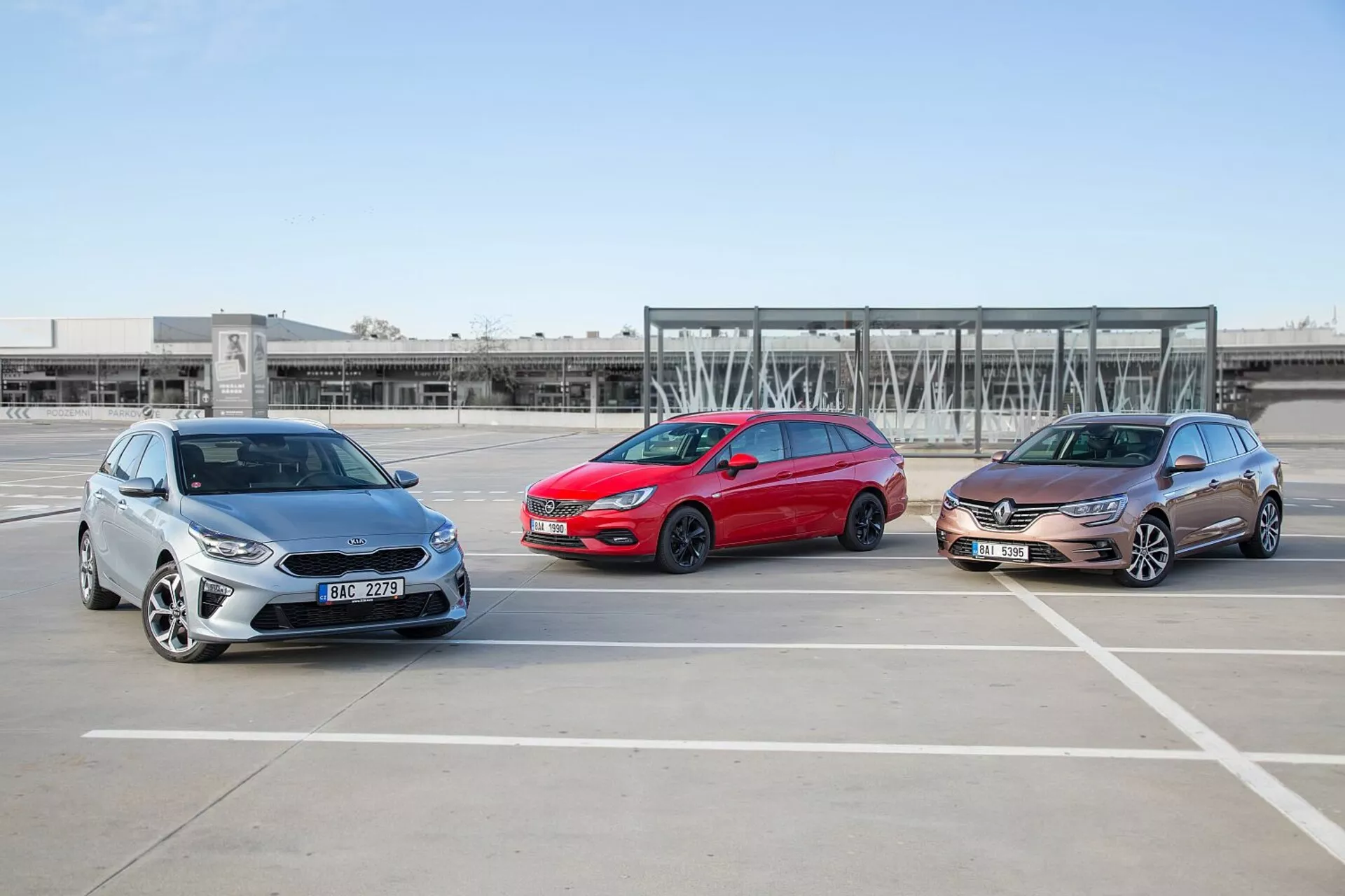 Tre modelli di Kia Ceed 2009, disposti in formazione sfalsata in un parcheggio vuoto, mostrano i loro profili frontali e laterali sotto condizioni atmosferiche limpide