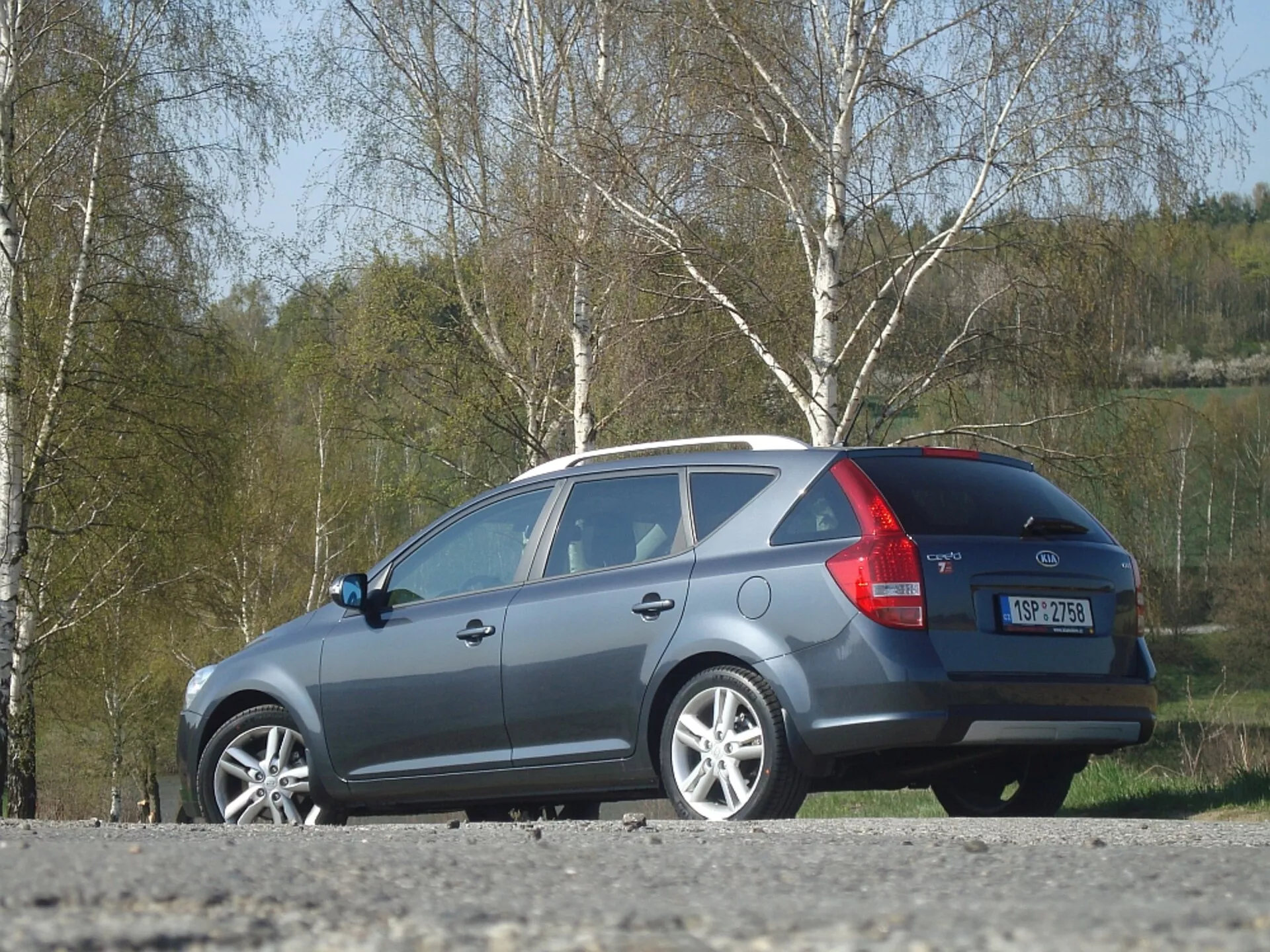 Station wagon Kia Ceed del 2009 in grigio, che mostra il design laterale e posteriore, con particolare attenzione alla linea del tetto aerodinamica, fanali posteriori e finestrino posteriore, parcheggiata all'aperto