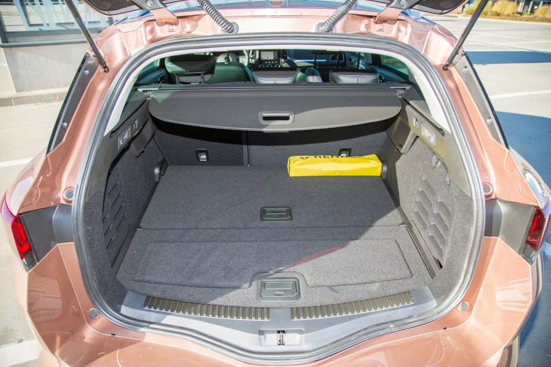Vista ravvicinata dello spazio bagagliaio di una Kia cee'd 2009 da un'angolazione dall'alto che mostra l'interno, il coperchio aperto, e il parabrezza posteriore parzialmente con copertura del carico retrattile, evidenziando la spaziosità e le caratteristiche di stoccaggio.