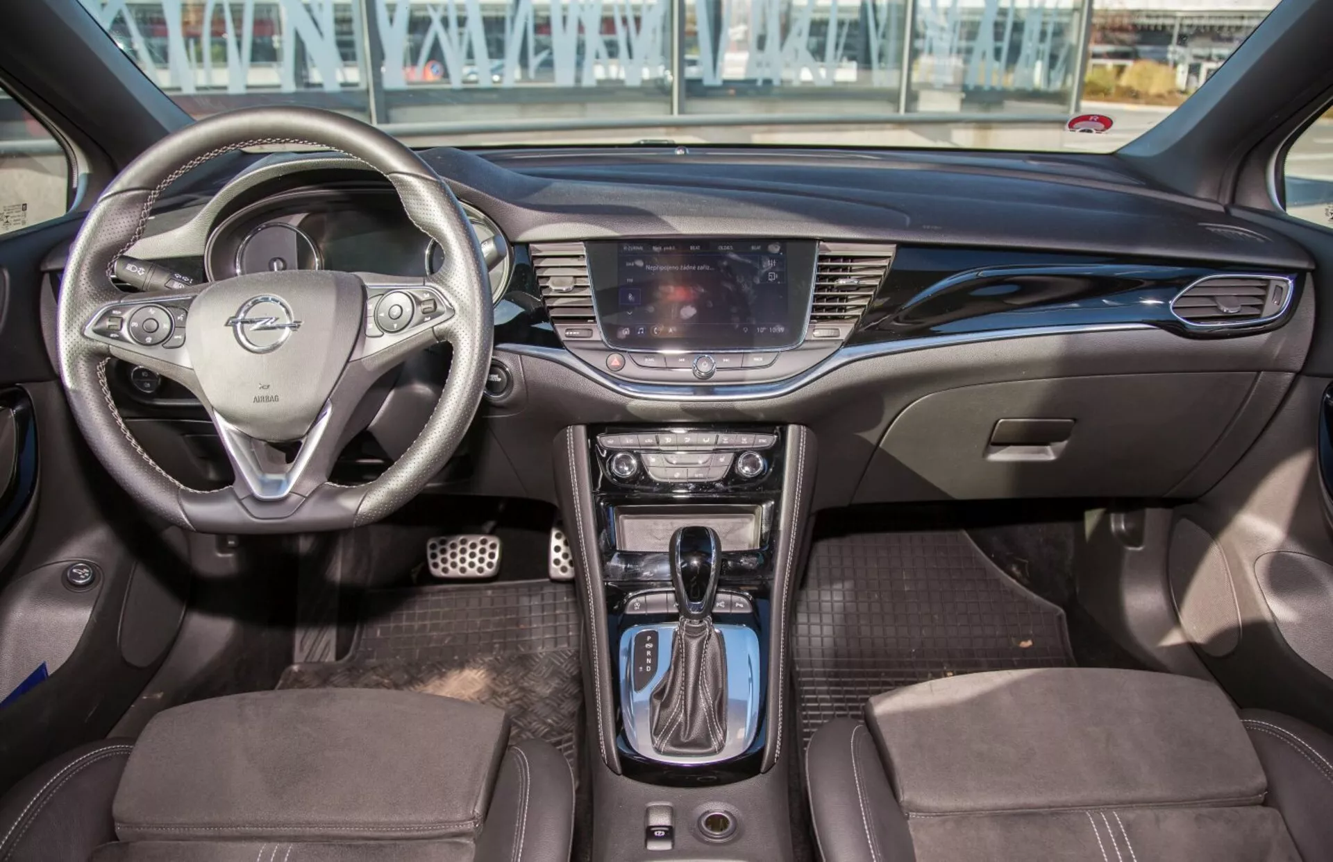 Interni della Kia Ceed 2009 con volante multifunzione, sistema di infotainment touch-screen, controlli del clima bizona, leva del cambio automatico, sedili rivestiti bicolore, e design moderno dell'abitacolo con dotazioni tecnologiche