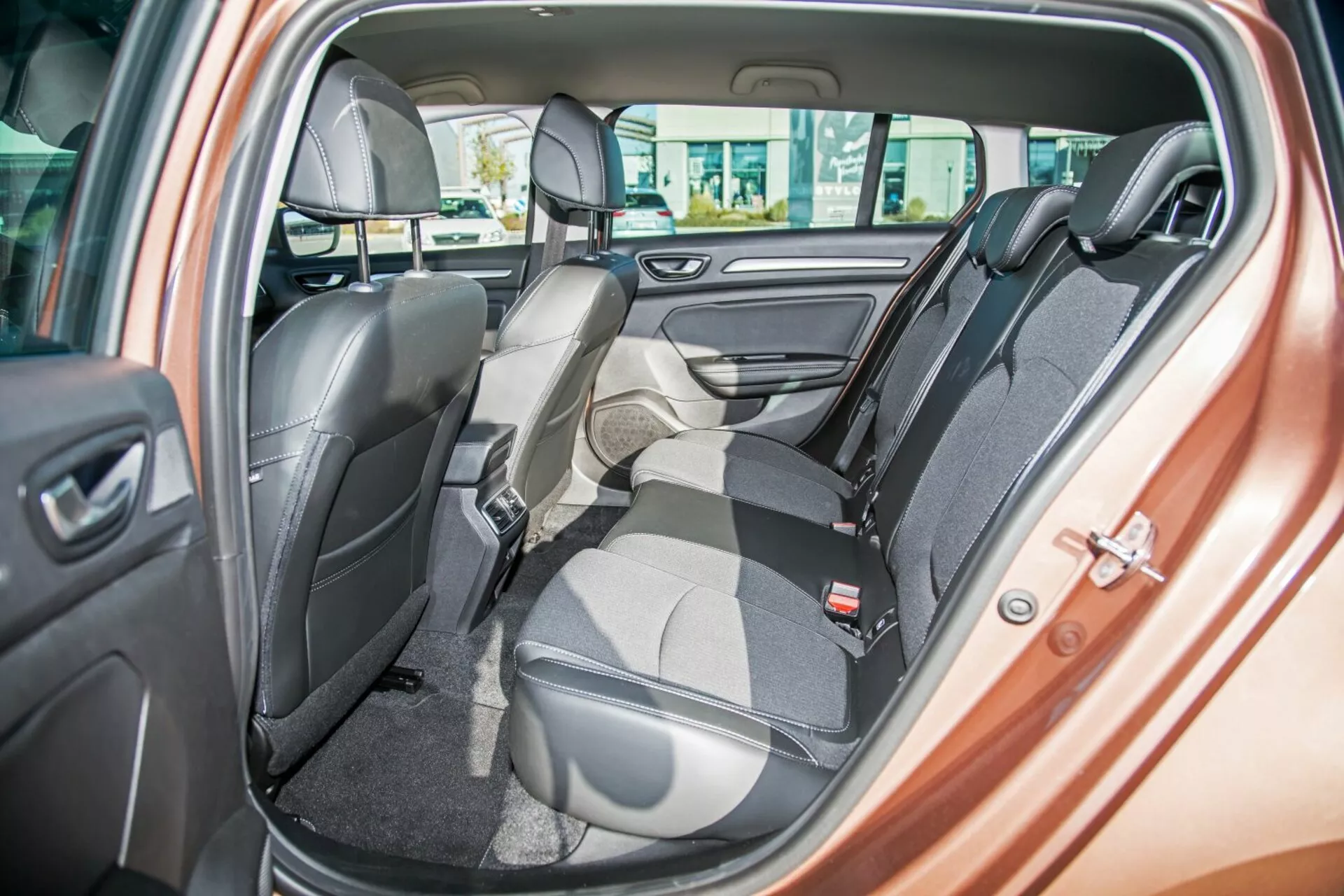 Interni della Kia Ceed 2009 con sedile posteriore bicolore con un sedile abbattuto in avanti per il carico, cinture di sicurezza, poggiatesta, comandi per i finestrini elettrici e altoparlante sulla porta, evidenziando sedili flessibili e design di lusso