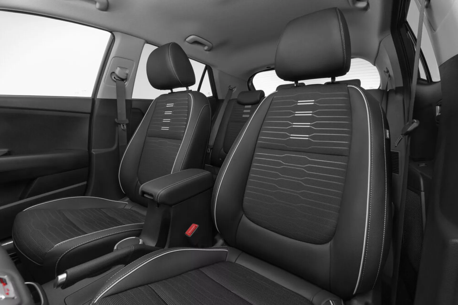 Vista ad angolo alto dell'interno anteriore della Kia Stonic 2017 che mostra sedili in similpelle nera con cuciture orizzontali, consolle centrale e punti di ancoraggio cinture di sicurezza rossi con un focus su design e disposizione