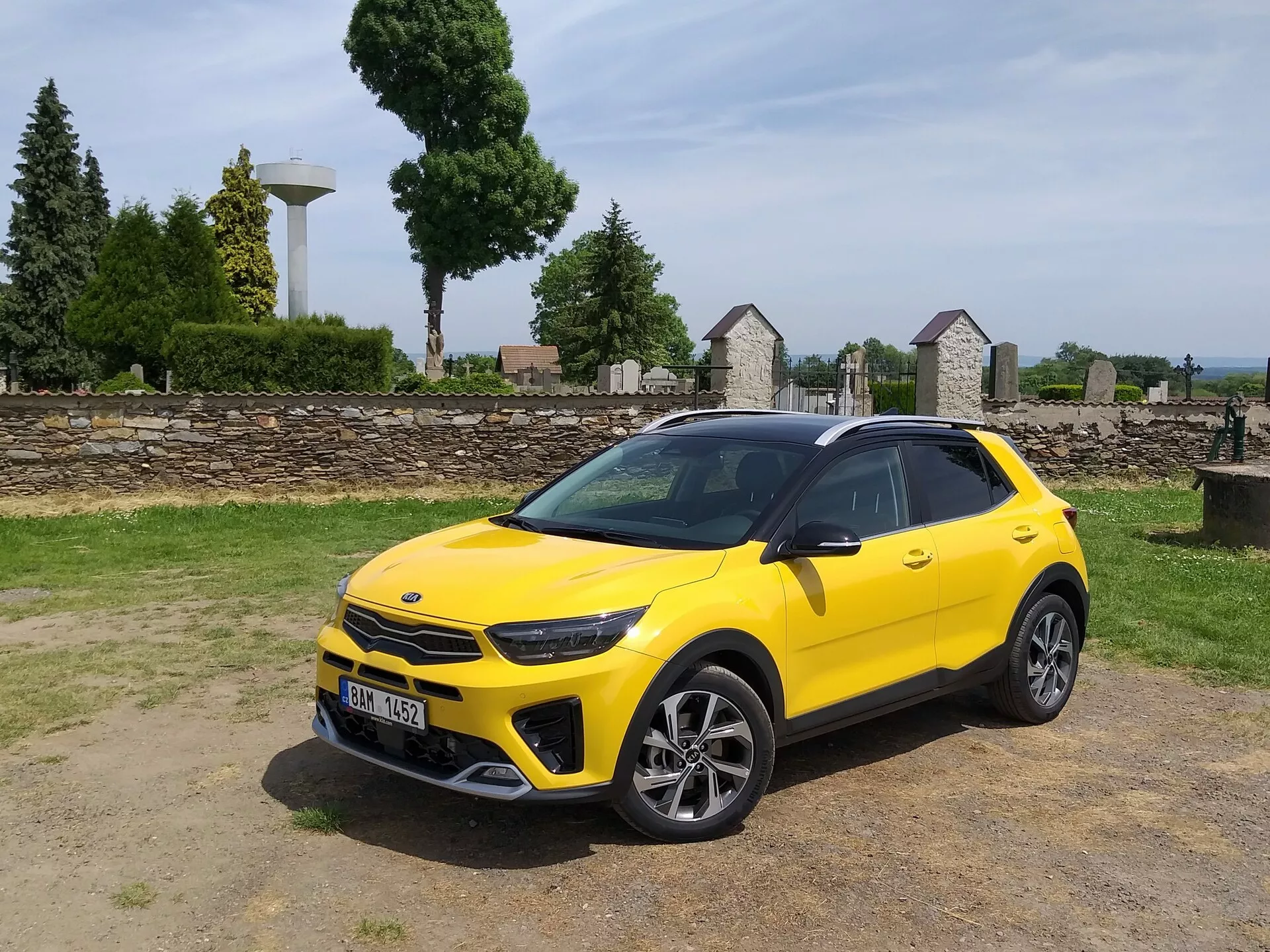 Kia Stonic 2017 in giallo brillante, mostrando la sua griglia anteriore, fari LED, paraurti anteriore sportivo e profilo laterale elegante con ruote in lega a più razze e barre sul tetto, evidenziando l'estetica del crossover compatto e le caratteristiche di design avanzate del veicolo.