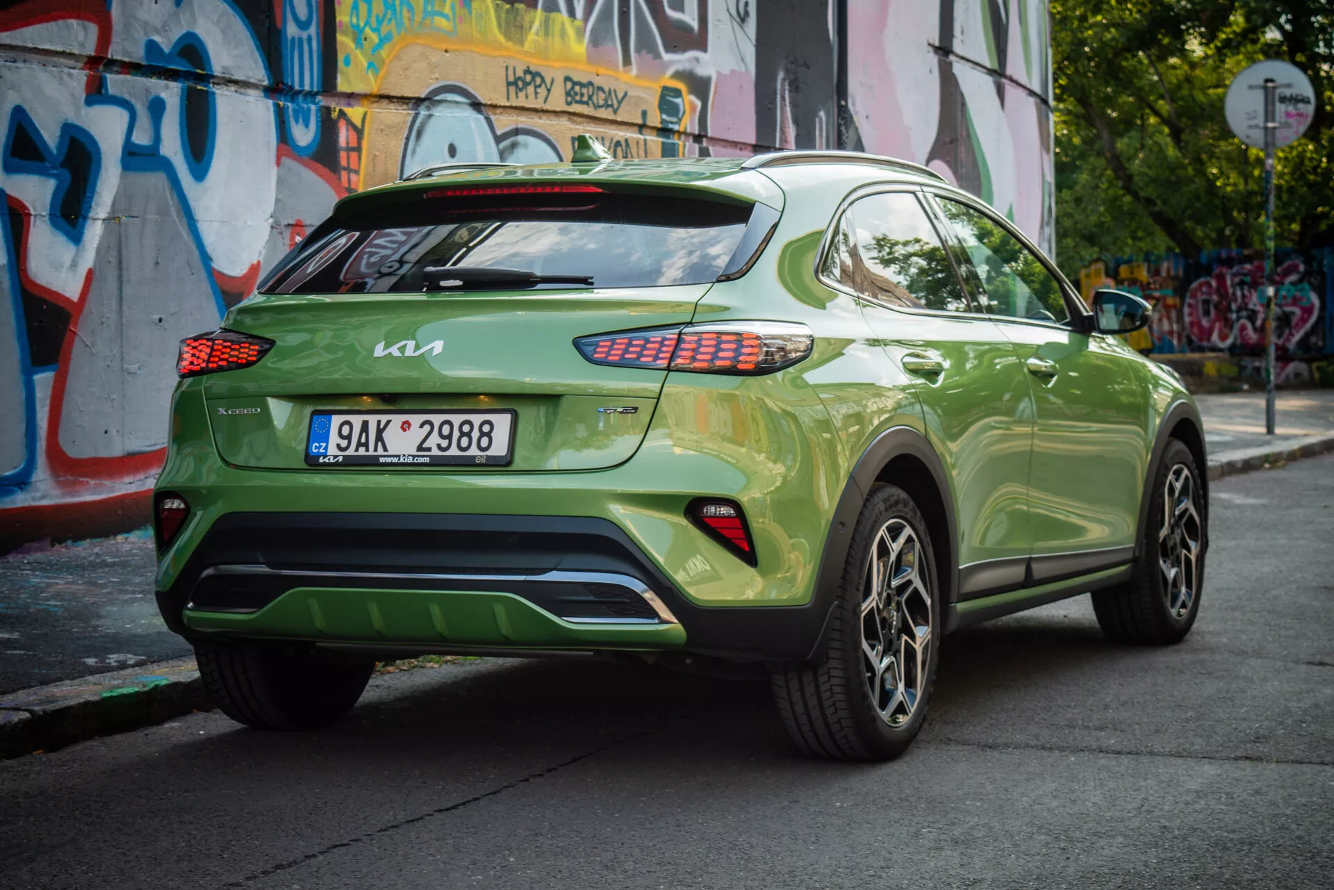 Kia XCeed 2022 in verde vibrante, mostra il suo angolo posteriore a tre quarti con targa europea, fari posteriori LED, ruote in lega e sfondo urbano.