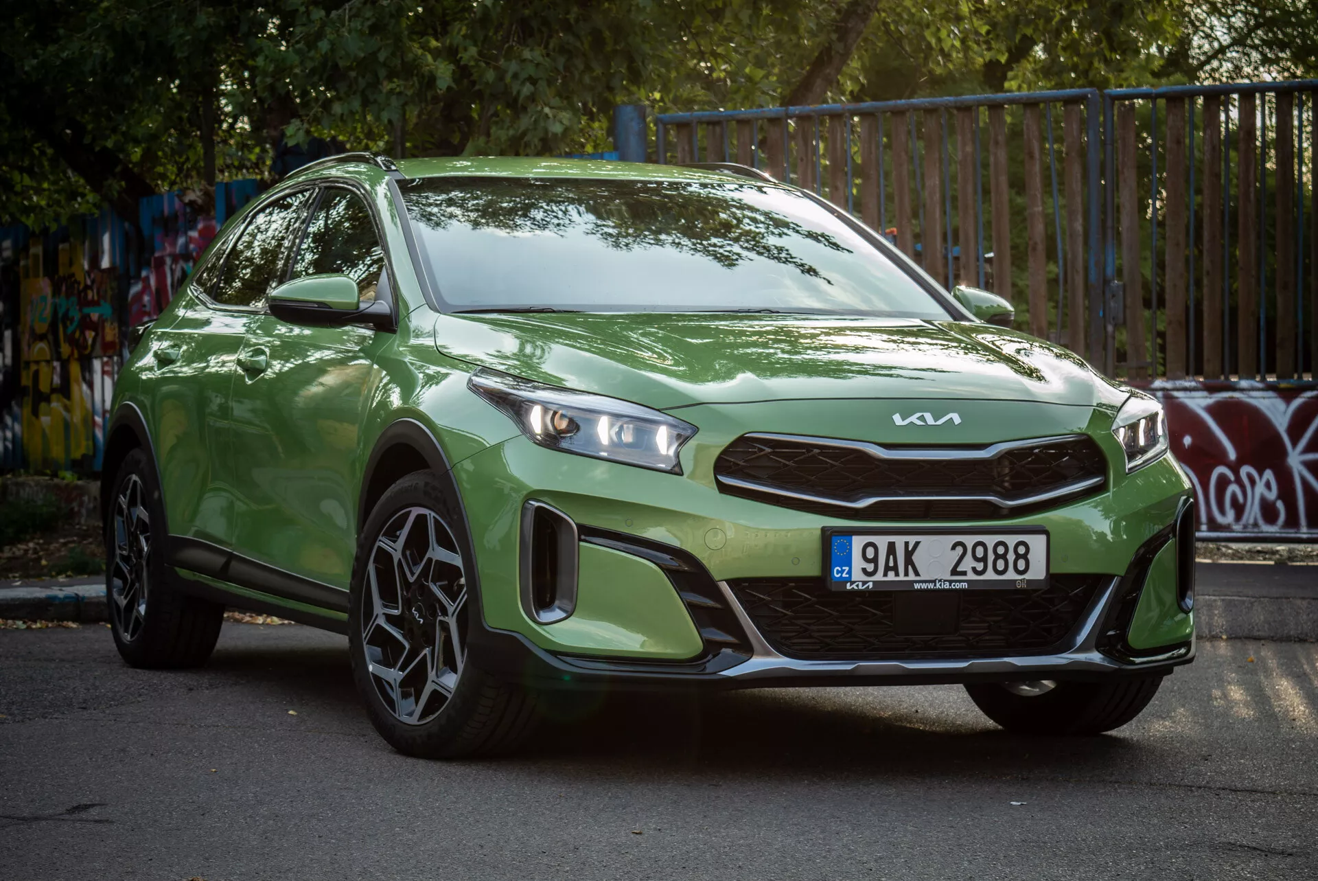 Kia Xceed 2022 verde parcheggiata in angolo, mostrando la sua vista frontale a tre quarti con fari LED e ruote in lega sportive in un contesto urbano