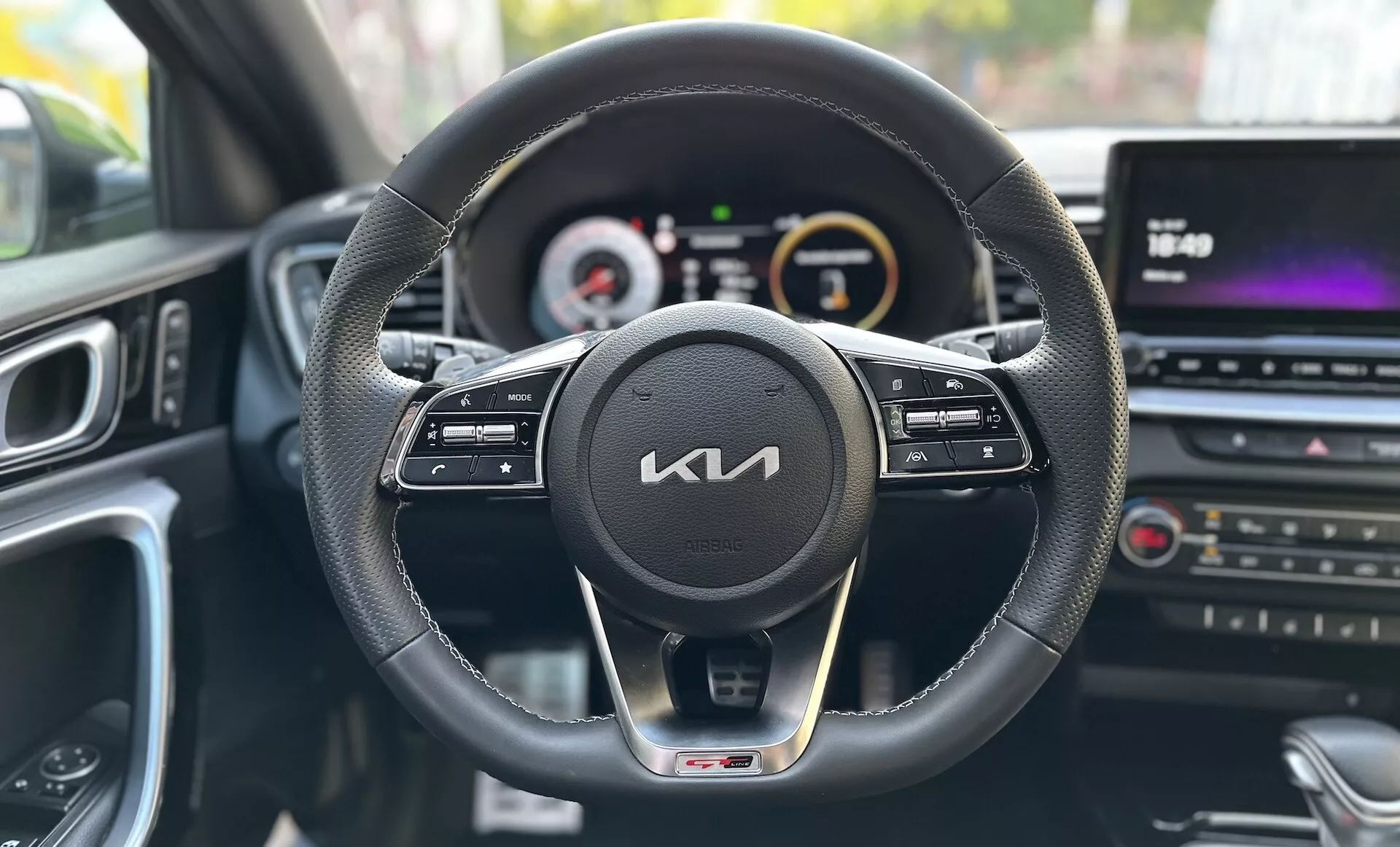 Vista dalla prospettiva del conducente all'interno di una Kia Xceed 2022 che mostra il cruscotto, il volante con pulsanti di controllo, il cluster strumenti digital-analogico e la console centrale multimediale