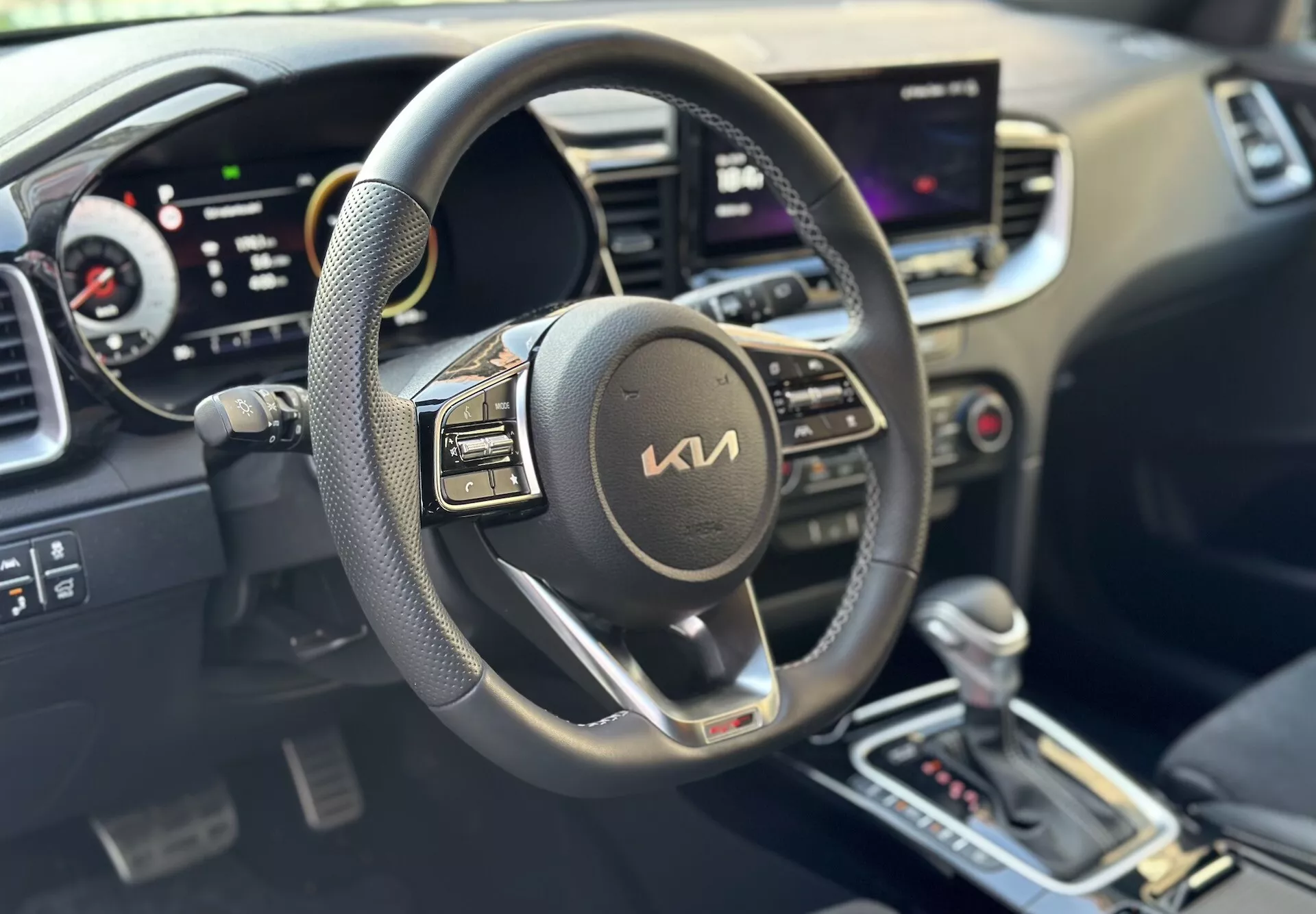 Interno della Kia Xceed 2022 focalizzato sul lato del conducente con volante, cruscotto digitale e sistema di infotainment centrale touchscreen che indica tecnologia moderna e comodità