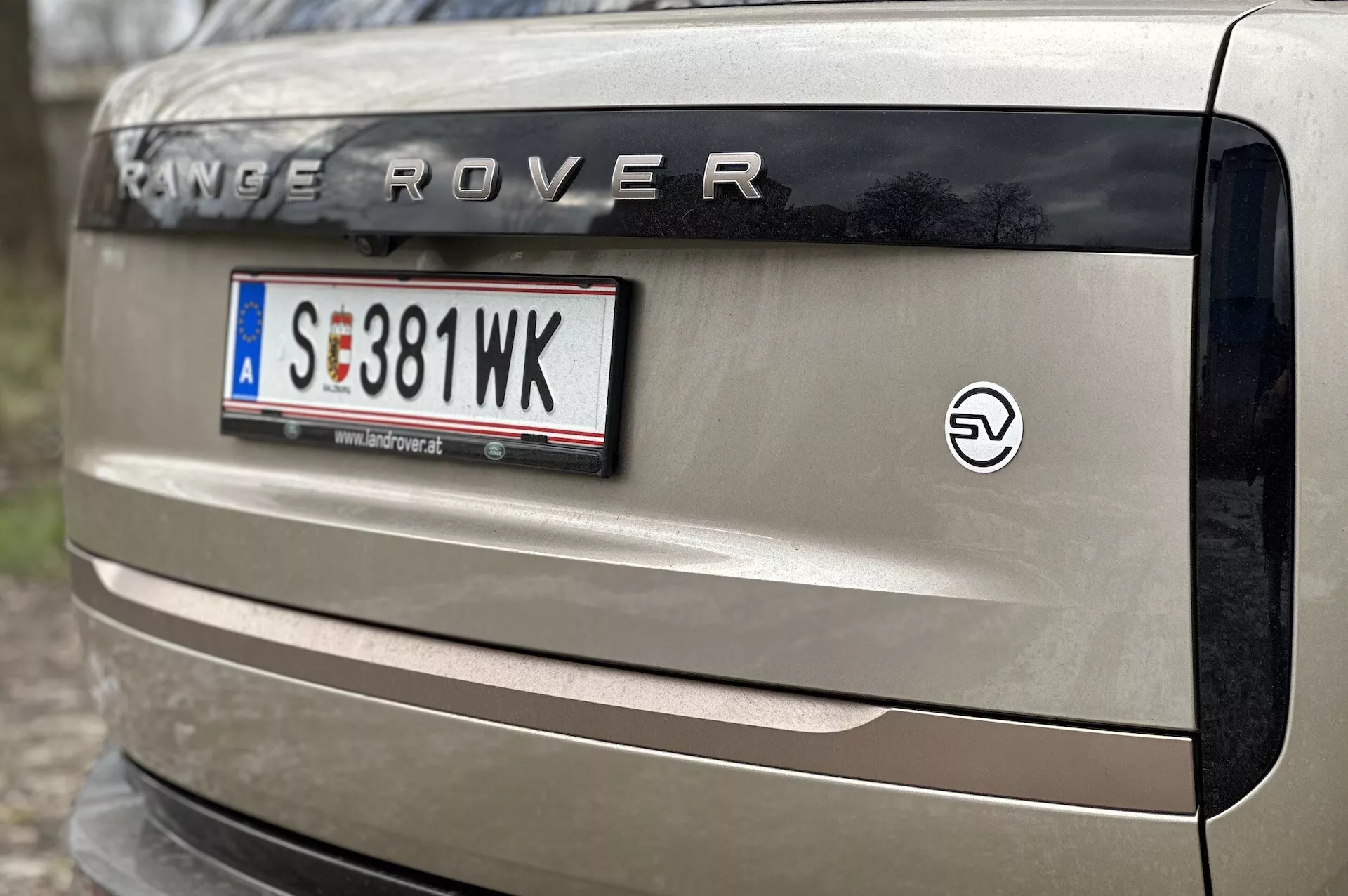 Vista ravvicinata del portellone di un Range Rover 2021 con marchio 'RANGE ROVER', targa in stile europeo, emblema EV e parte del faro posteriore