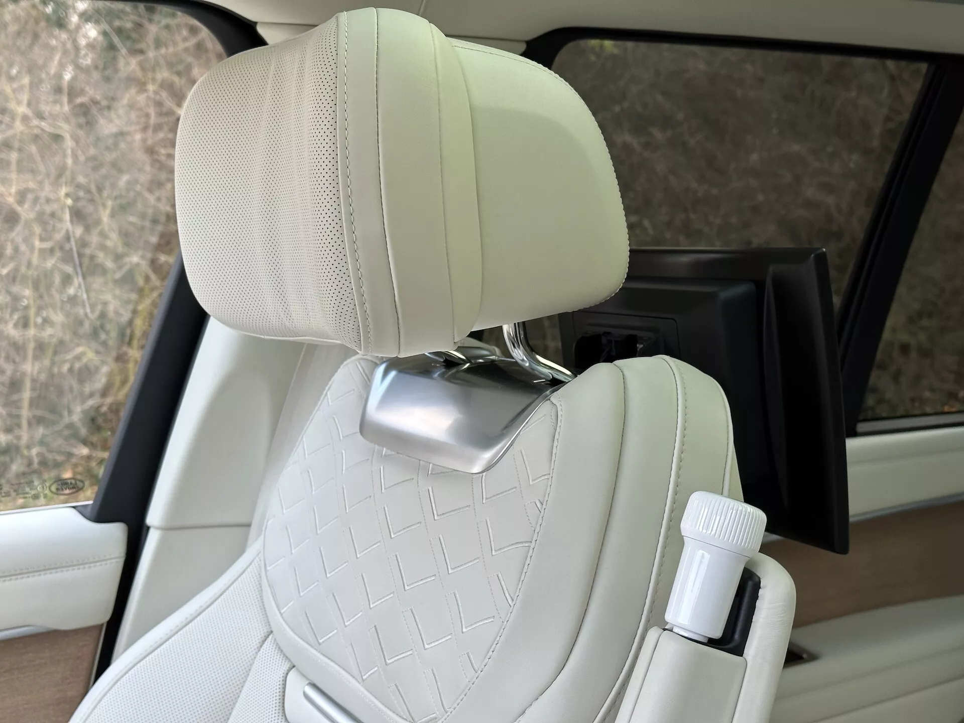 Vista interna della Land Rover Range Rover 2021 che evidenzia il sedile del passeggero in pelle crema trapuntata con supporto per la testa in cromo e portabottiglie sul lato porta, mostrando design del veicolo di lusso e caratteristiche di comfort