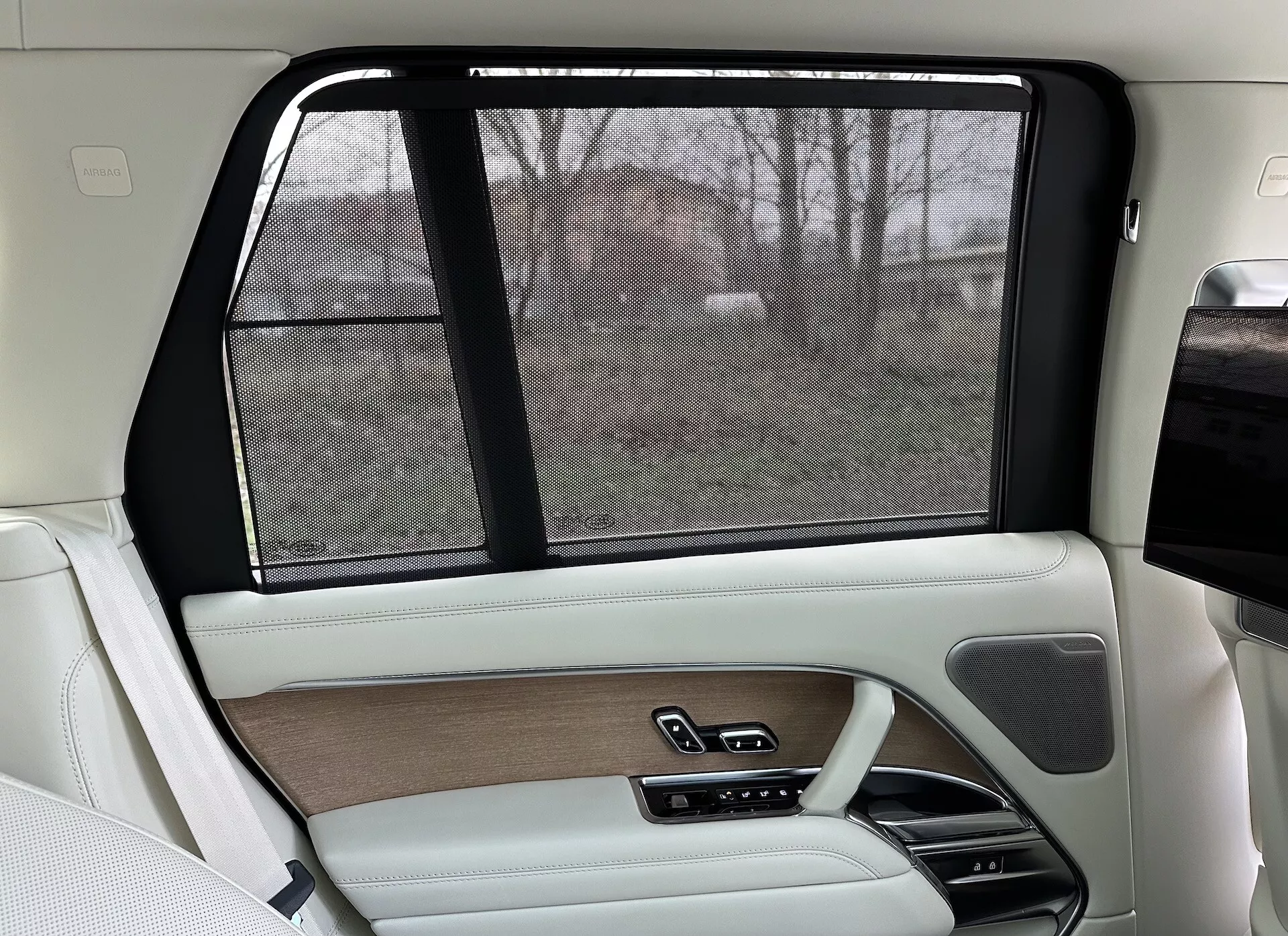 Interno lato passeggero posteriore di una Land Rover Range Rover 2021, con design lussuoso in beige e nero, inserti in legno, finiture in pelle, parasole elettronico e sistemi di controllo avanzati