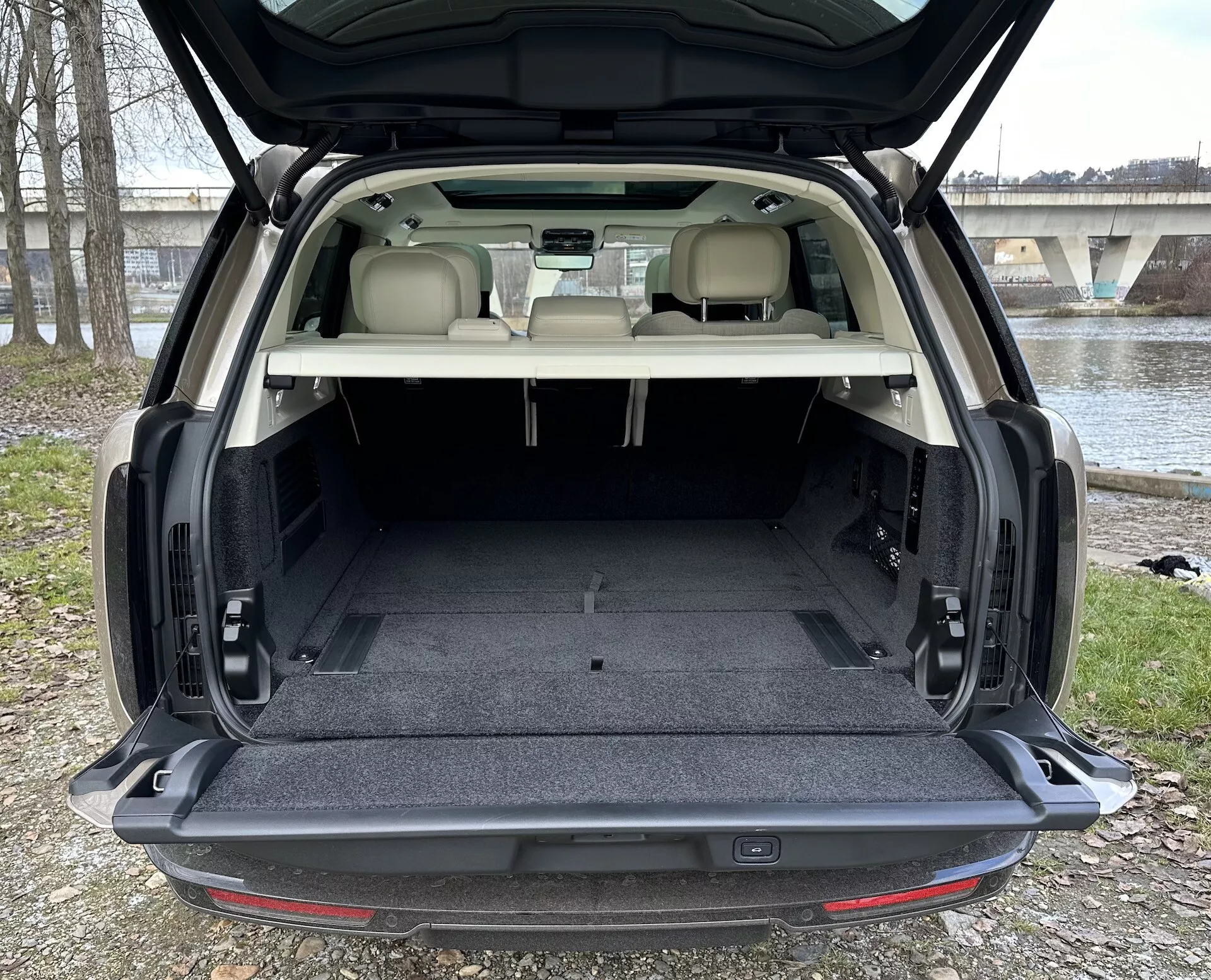 SUV Land Rover Range Rover 2021 che mostra l'ampia area di carico posteriore con portellone aperto, tappezzeria chiara a contrasto con tappeto scuro, e caratteristiche interne tra cui illuminazione dell'area di carico e possibili meccanismi di ripiegamento dei sedili