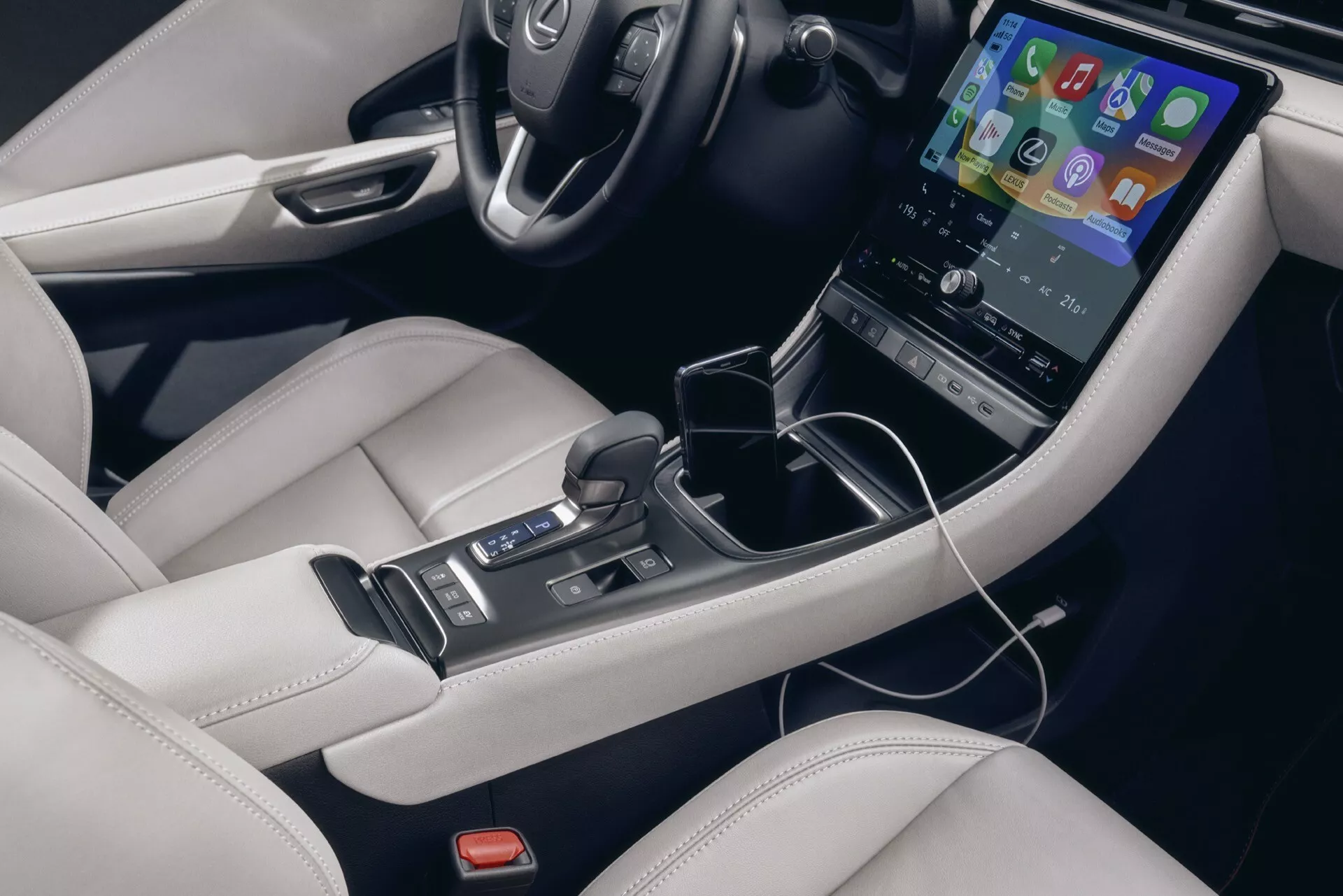 Interno della Lexus LBX 1ª generazione 2024 che mostra una vista dettagliata della console centrale con touchscreen verticale, leva del cambio automatico e tappezzeria in pelle di lusso
