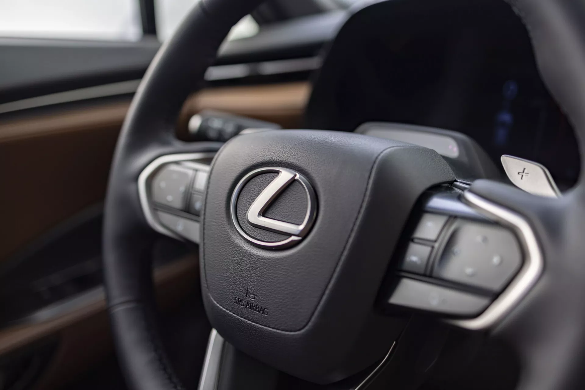 Vista ravvicinata del volante della Lexus LBX 2024 che concentra l'attenzione sul logo Lexus e sui pulsanti di controllo, enfatizzando lusso e tecnologia avanzata
