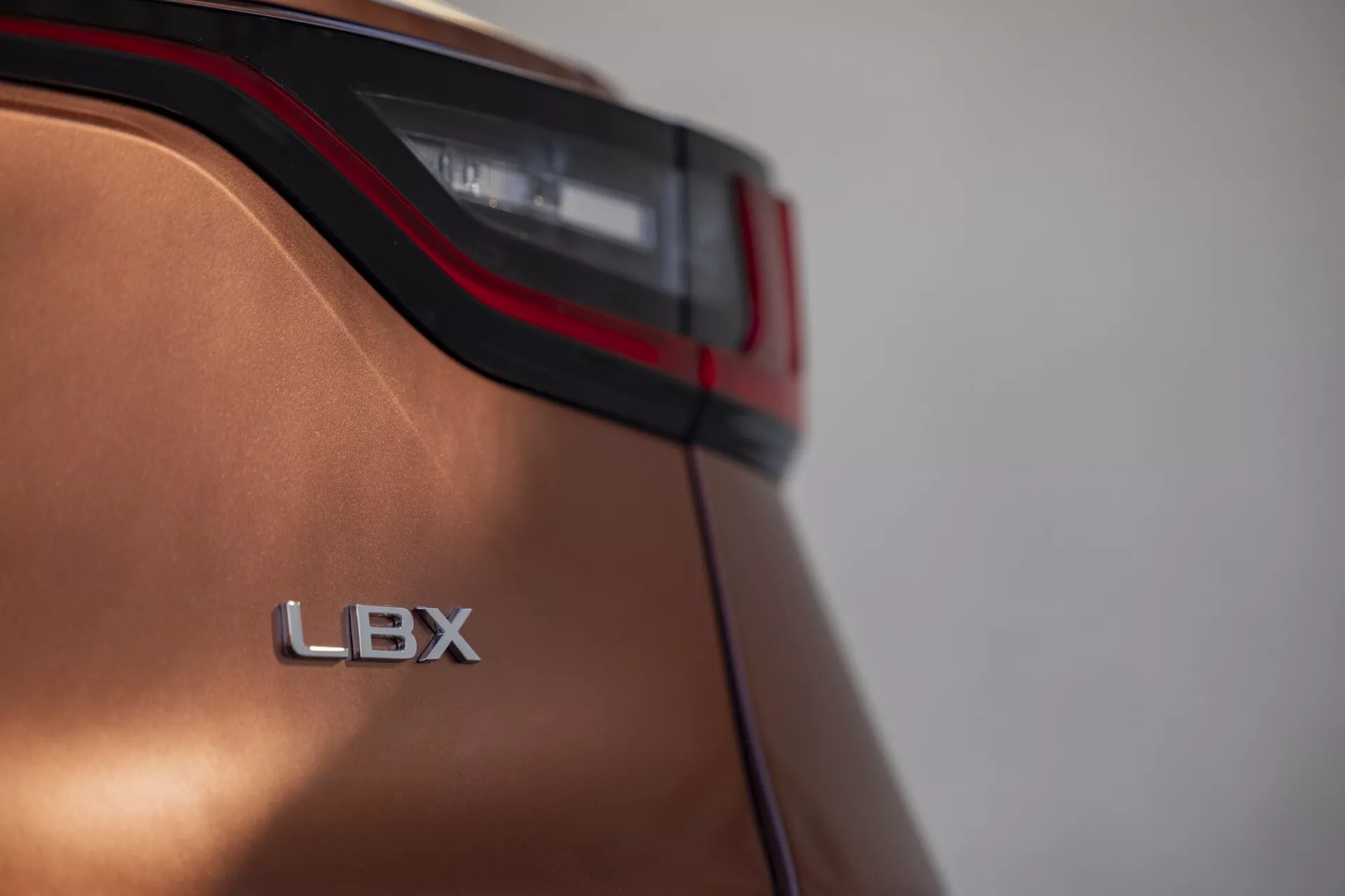 Primo piano del quarto posteriore del Lexus LBX 2024 con dettaglio della luce posteriore a LED e badge LBX con finitura metallica e design aerodinamico