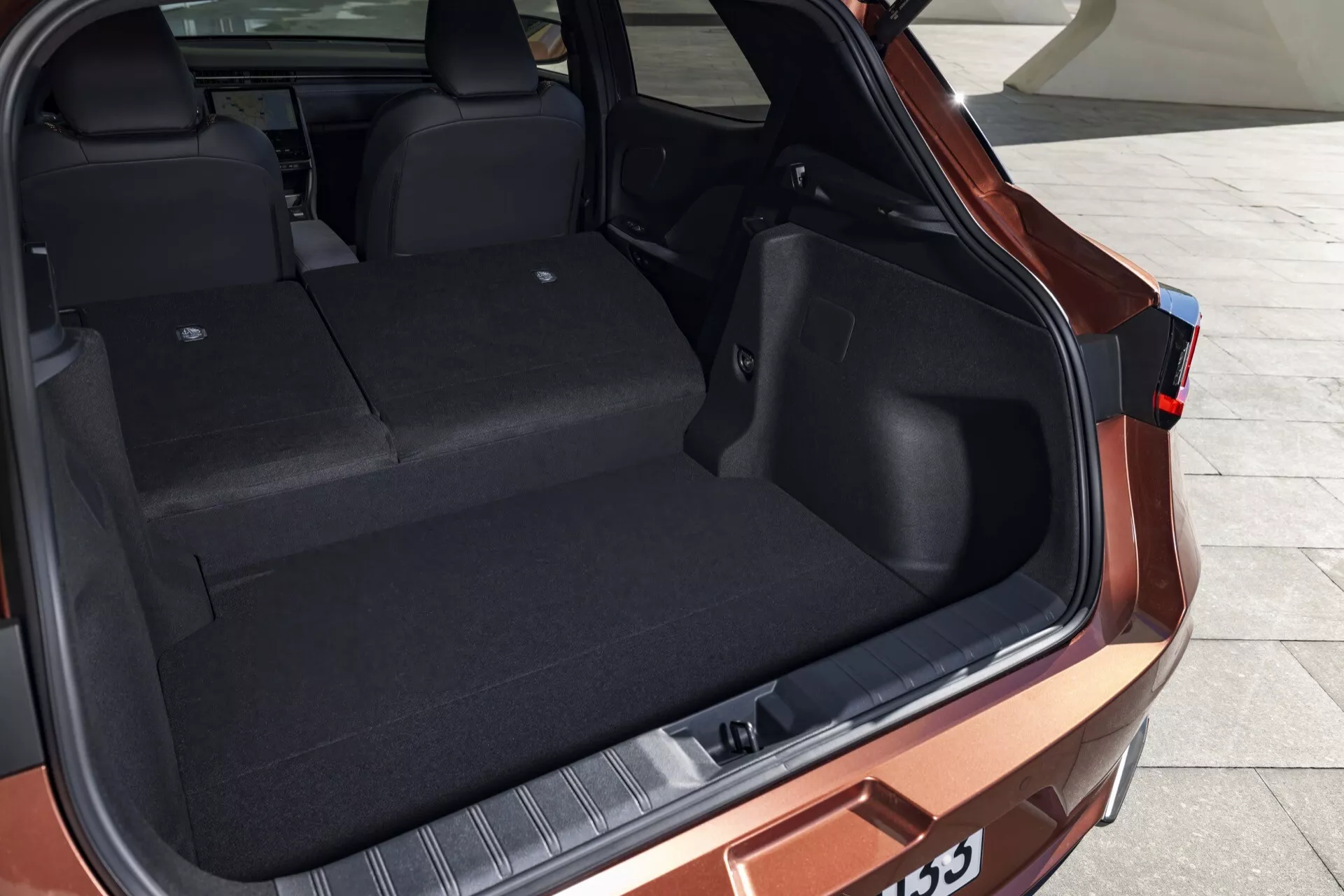 Lexus LBX 1ª generazione 2024 mostra lo spazio di carico posteriore da una prospettiva posteriore di tre quarti, evidenziando la grande capacità del bagagliaio, design interno resistente e caratteristiche esterne moderne senza presenza umana.