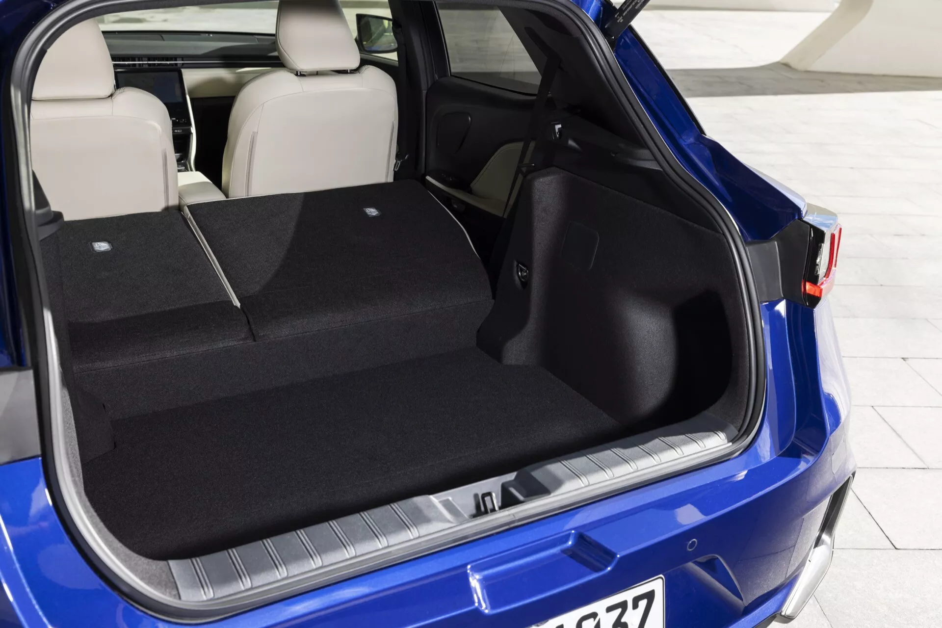 Vista del vano posteriore di Lexus LBX 1ª generazione 2024 con portellone aperto, mostrando la spaziosa area di carico, la protezione su paraurti, design sedile posteriore sdoppiabile in un colore blu vivace