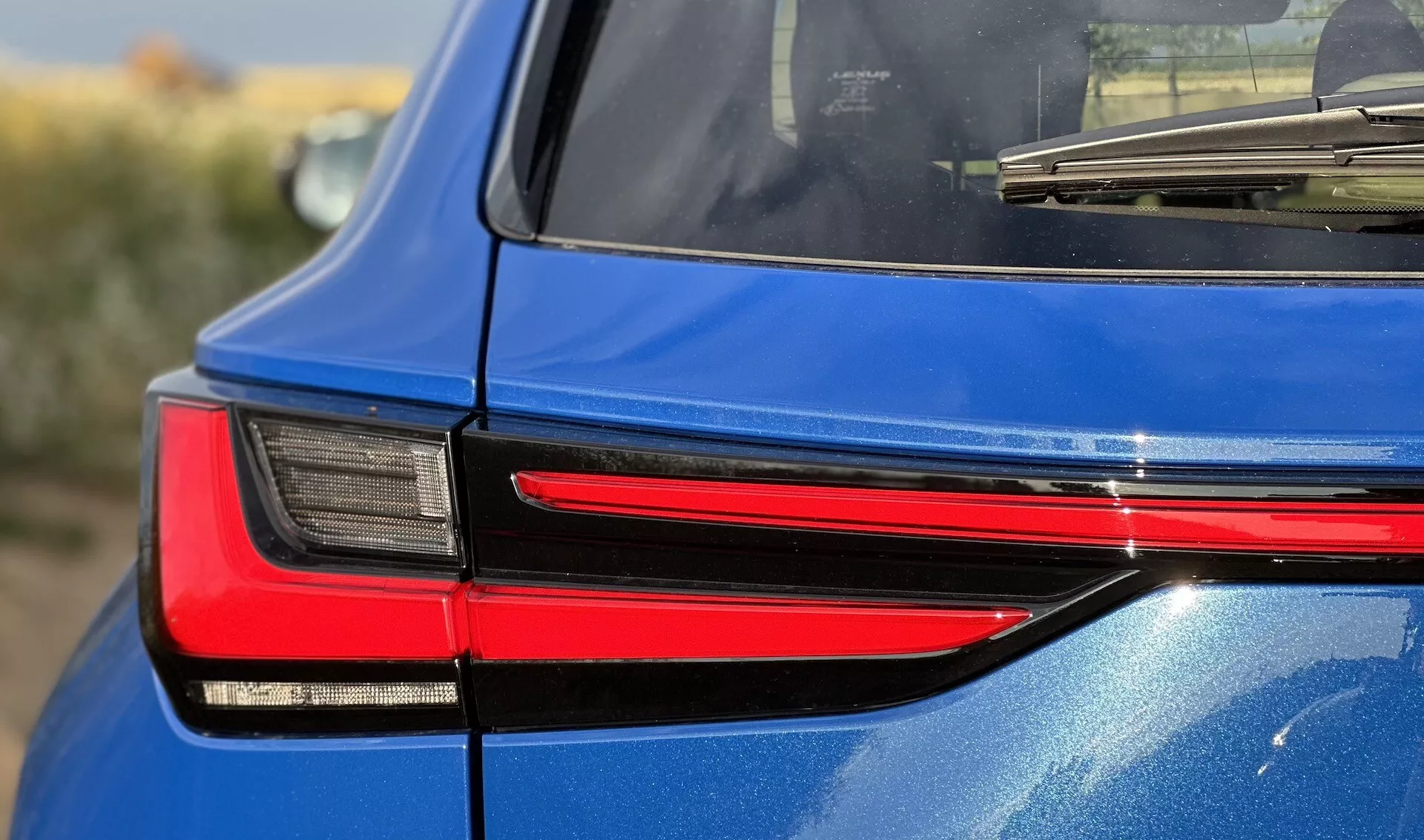 Vista dettagliata della parte posteriore destra di un Lexus NX 2021, che mette in mostra il moderno design della luce posteriore LED, riflettendo la sua sofisticata tecnologia di illuminazione e finitura blu lucida.