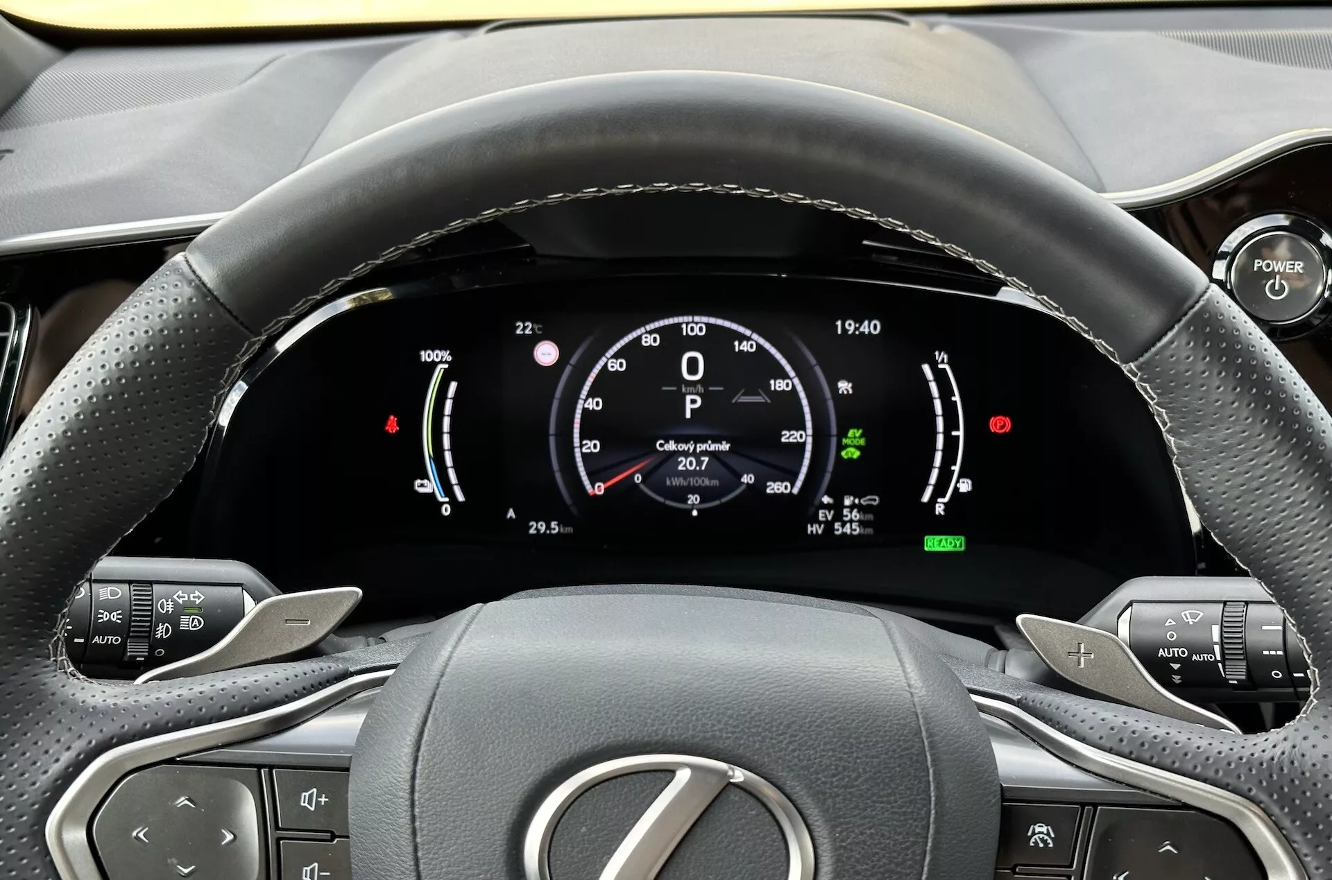 Vista dal posto di guida del volante e del cruscotto digitale della Lexus NX 2021, con indicatori della tecnologia ibrida, pulsanti di controllo comfort e design interno ergonomico