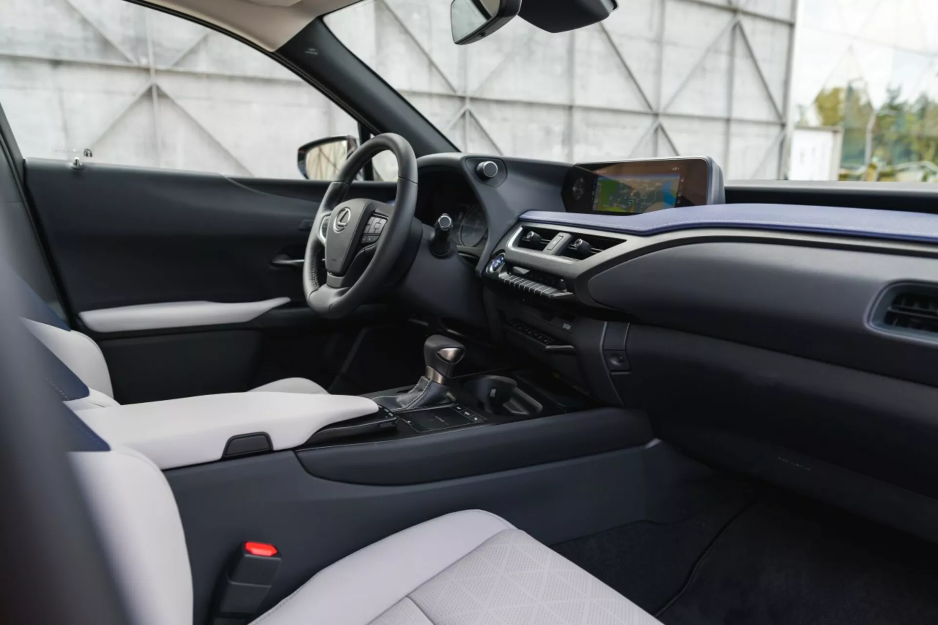 Interni moderni del Lexus UX 2019 con design bicolore, volante multifunzione, schermo infotainment sporgente e trasmissione automatica da una prospettiva decentrata, all'altezza degli occhi