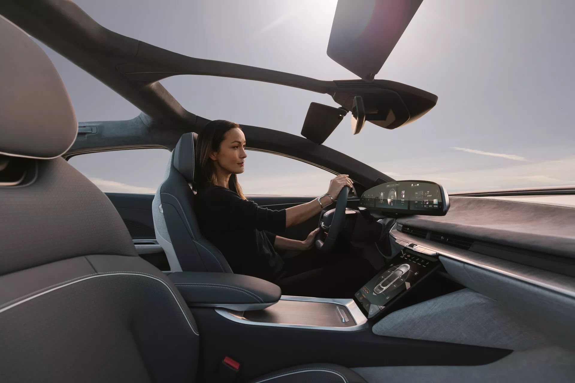 Vista interna del Lucid Air 2022 dal lato passeggero, che mostra il moderno sedile del conducente e il cruscotto avanzato con display digitali e controlli touchscreen, evidenziando un design lussuoso e tecnologicamente avanzato