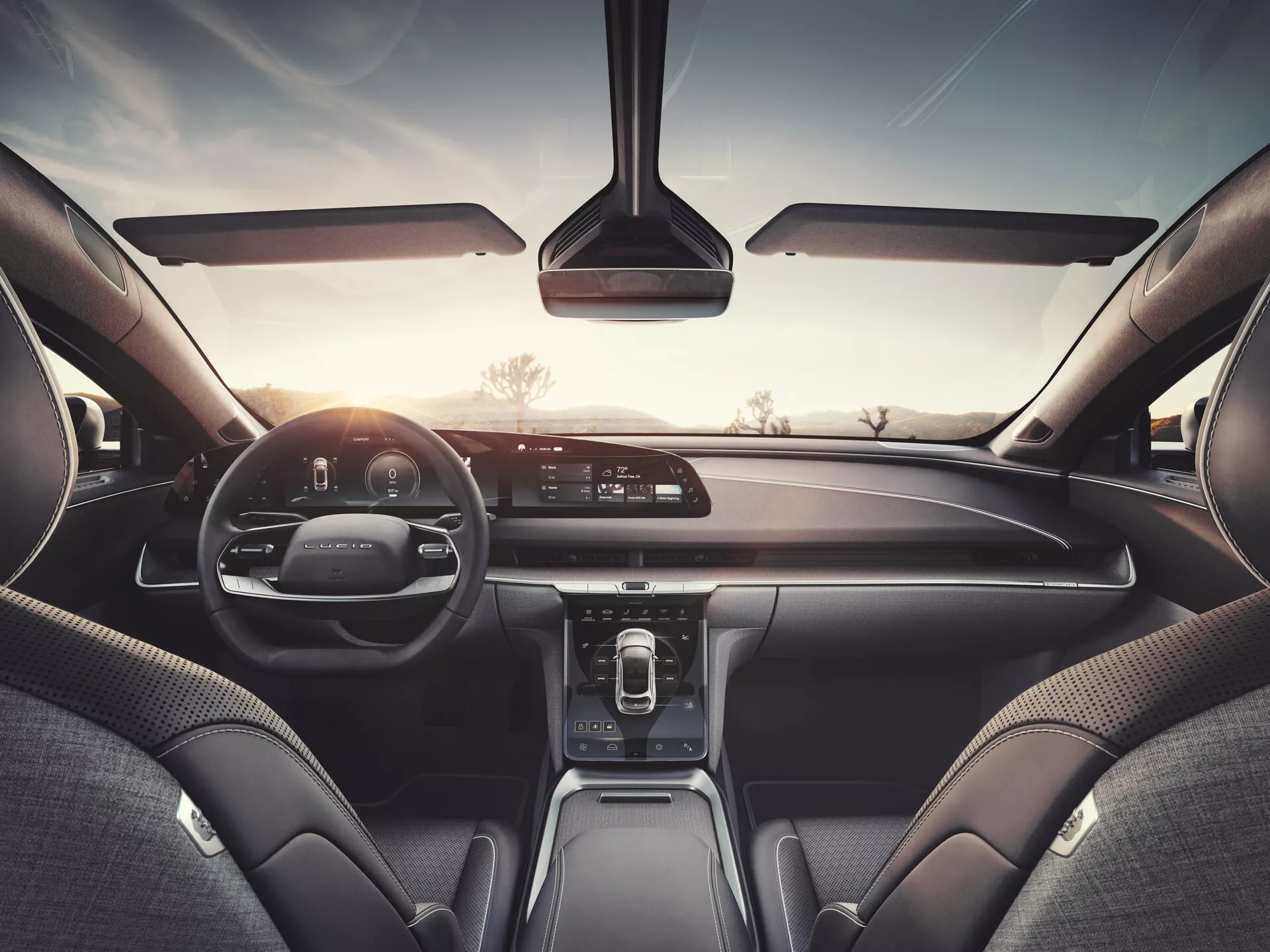 Vista interna di una Lucid Air 2022 dal sedile posteriore, che mostra il cruscotto, il display infotainment, il quadro strumenti digitale e materiali premium in pelle che suggeriscono un modello di fascia alta con un avanzato sistema multimediale, controlli climatici e tecnologie di connettività.
