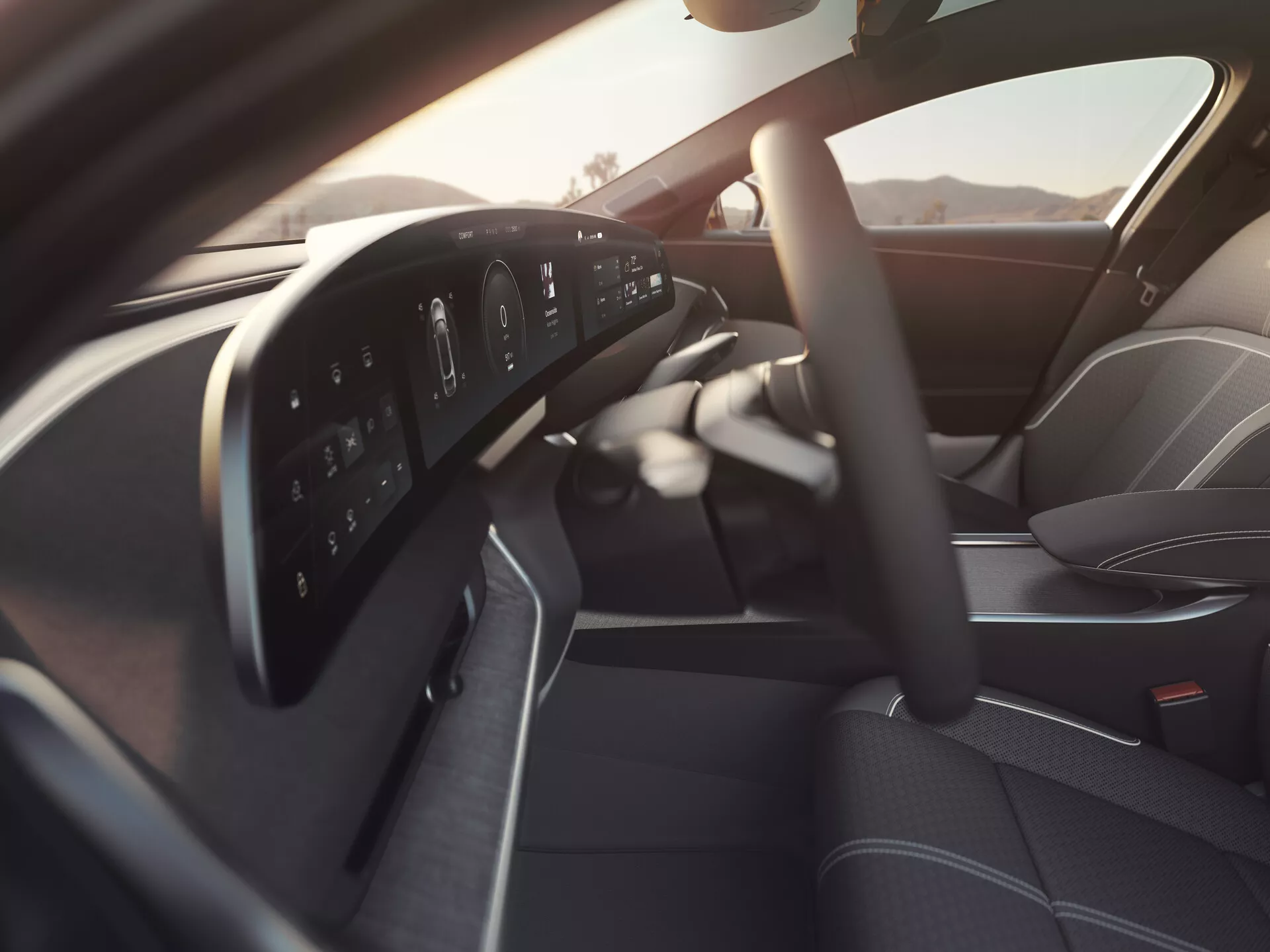 Interni della Lucid Air 2022 di prima generazione visti dal lato passeggero, con un volante multifunzione moderno con pulsanti di controllo, un cruscotto completamente digitale, parte della console centrale elegante, sedile del conducente sagomato di alta qualità e pannello porta del conducente con comandi per finestre e specchi elettrici, il tutto illuminato da una luce naturale soffusa.