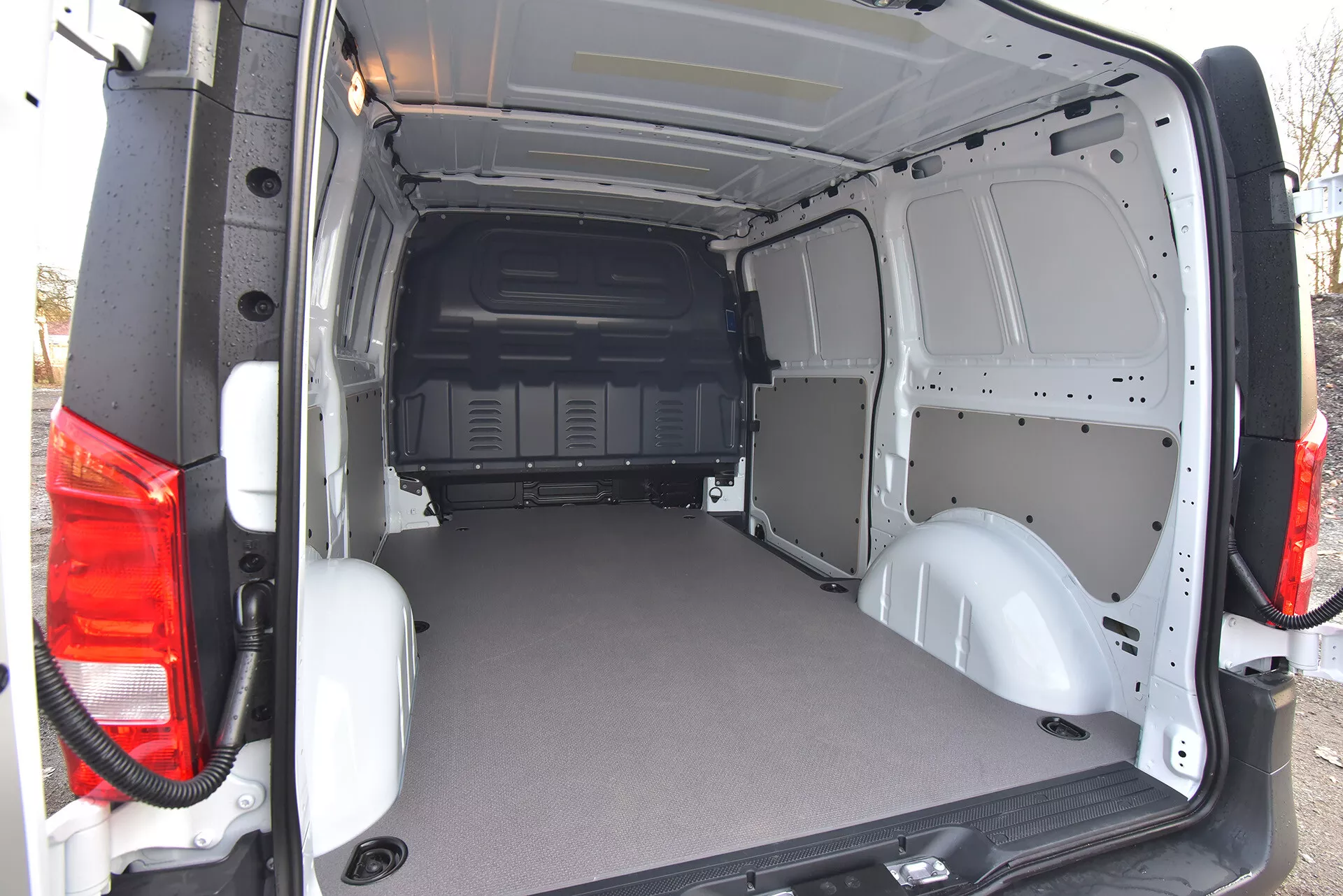 Area di carico posteriore del furgone commerciale Mercedes-Benz Vito Tourer 2014 con porte aperte che mostrano un pavimento pianeggiante e resistente e un interno in metallo a vista per una facile personalizzazione, vista da un angolo esterno posteriore obliquo