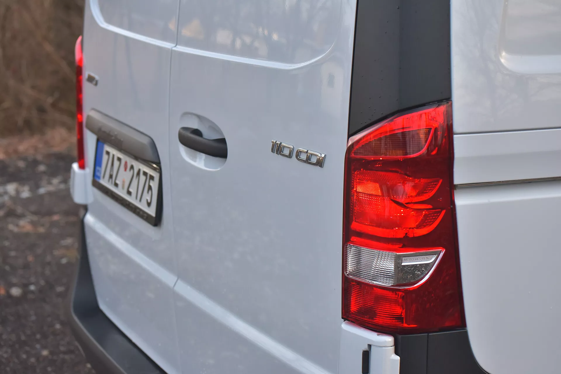 Vista del angolo posteriore destro di un furgone Volkswagen Vito 2014 Tourer in argento o grigio chiaro che mostra fanale posteriore, badge del modello 'VW CADDY', targa in stile europeo '12-TZ-4715' e design del corpo squadrato tipico delle furgoni da carico compatti.