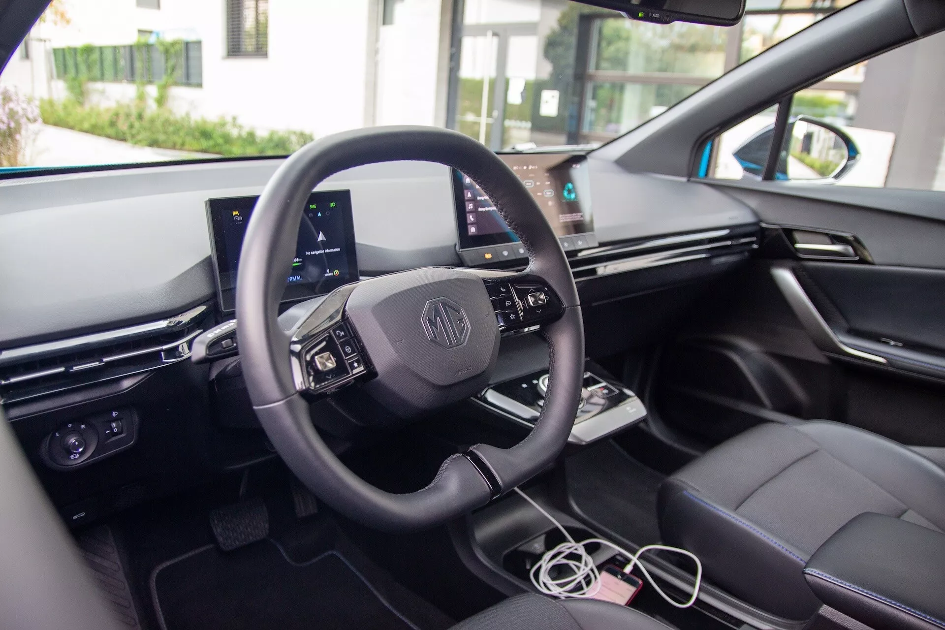 Vista interna della MG MG4 2022 che mostra il cruscotto orientato al conducente, volante rivestito in pelle con comandi integrati, cluster strumenti digitale, e touchscreen centrale per l'infotainment