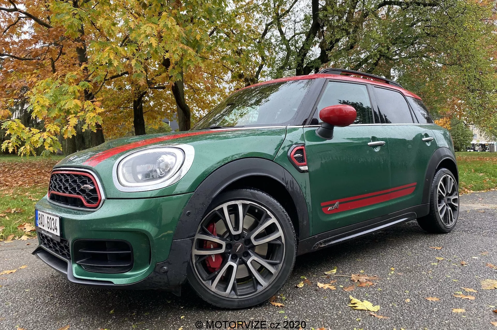 Vista frontale a tre quarti dal basso di una Mini Countryman John Cooper Works 2020, che mostra il suo esterno verde scuro con dettagli rossi, cerchi sportivi a più razze, griglia con cornice cromata, ampie prese d'aria, fari a LED e pinze dei freni rosse.