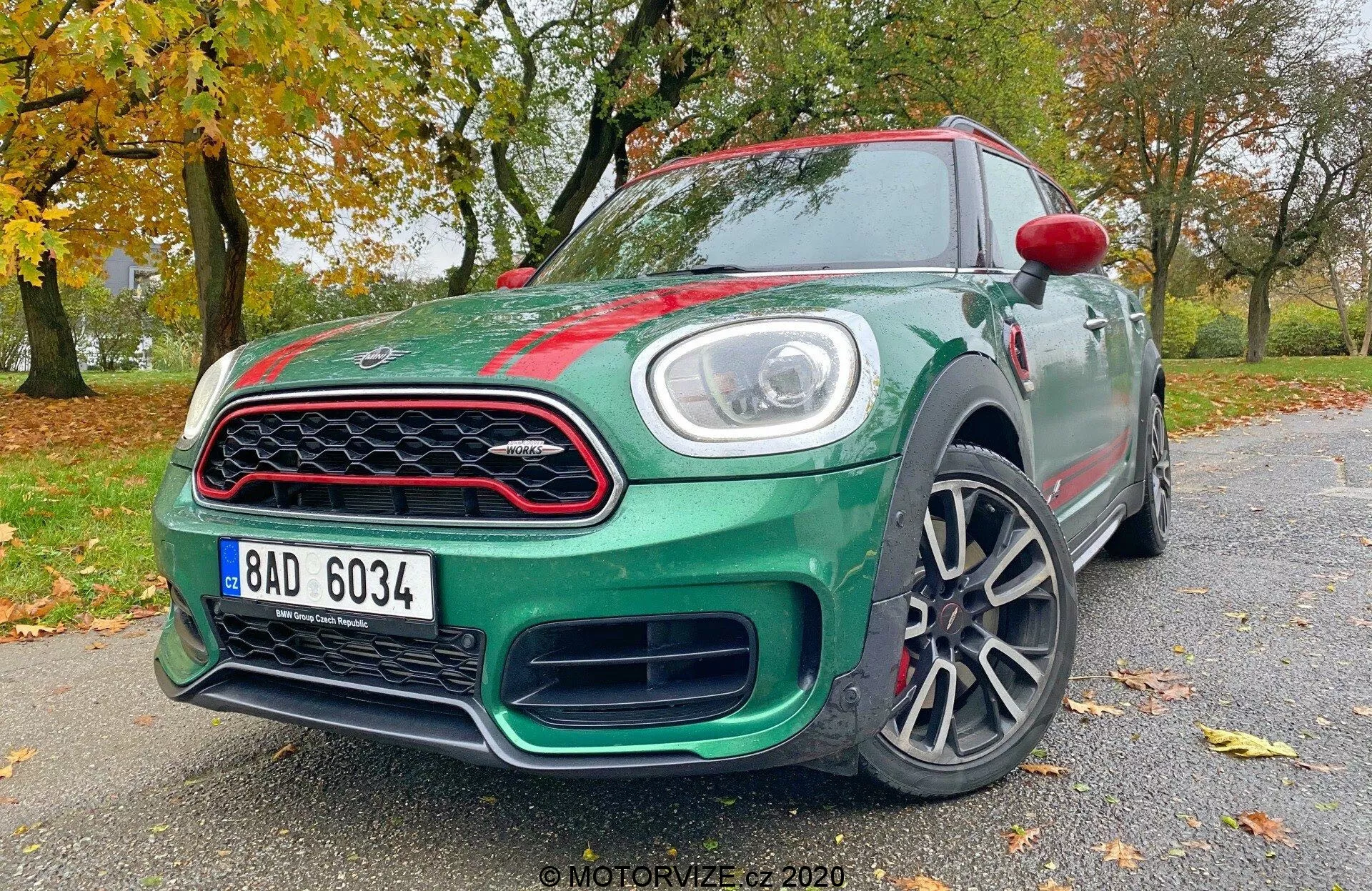 L'immagine mostra una Mini Countryman John Cooper Works hatchback del 2020, ripresa da un'angolazione bassa frontale di tre quarti. Sono visibili elementi chiave di design e tecnologia come i fari a LED, la distintiva griglia anteriore, il paraurti stilizzato, i cerchi in lega, gli specchietti laterali parzialmente visibili con indicatori di direzione integrati, le linee aerodinamiche del corpo, i badge e la finitura della vernice lucida dell'auto. Questa prospettiva enfatizza la posizione aggressiva e il design dinamico del veicolo.